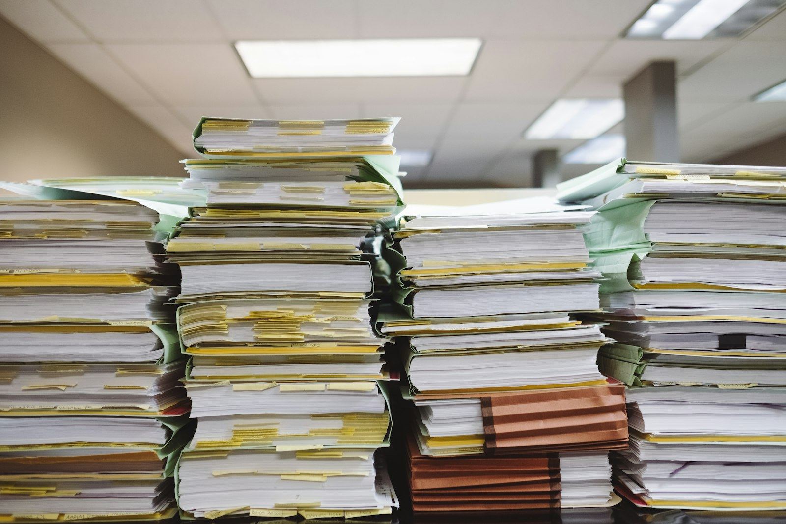 Stacks of paper files and folders on an office desk