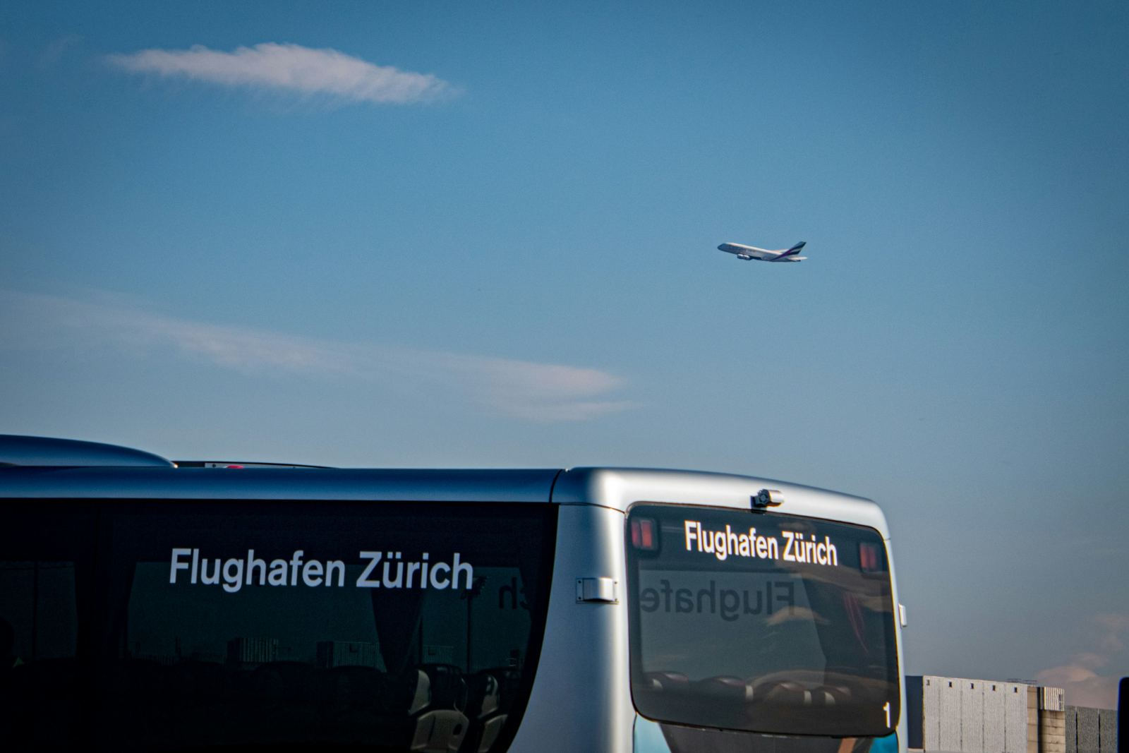 White airport shuttle bus parked in front of a terminal building