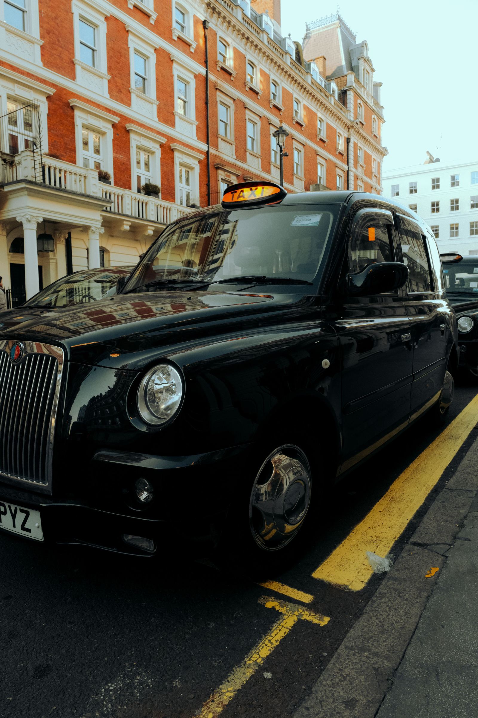 Front view of a black London taxi cab with its TAXI sign lit