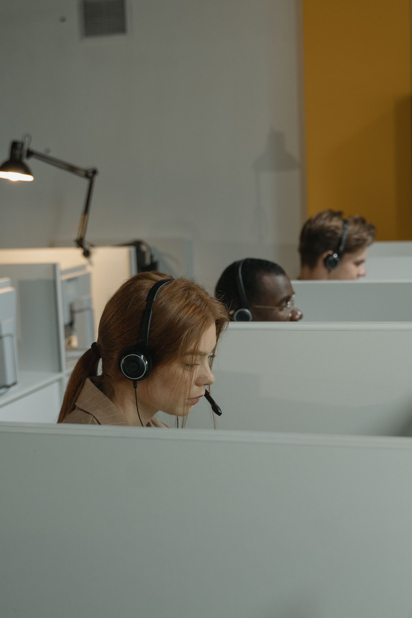 Dispatchers wearing headsets working at desks in a row of office cubicles