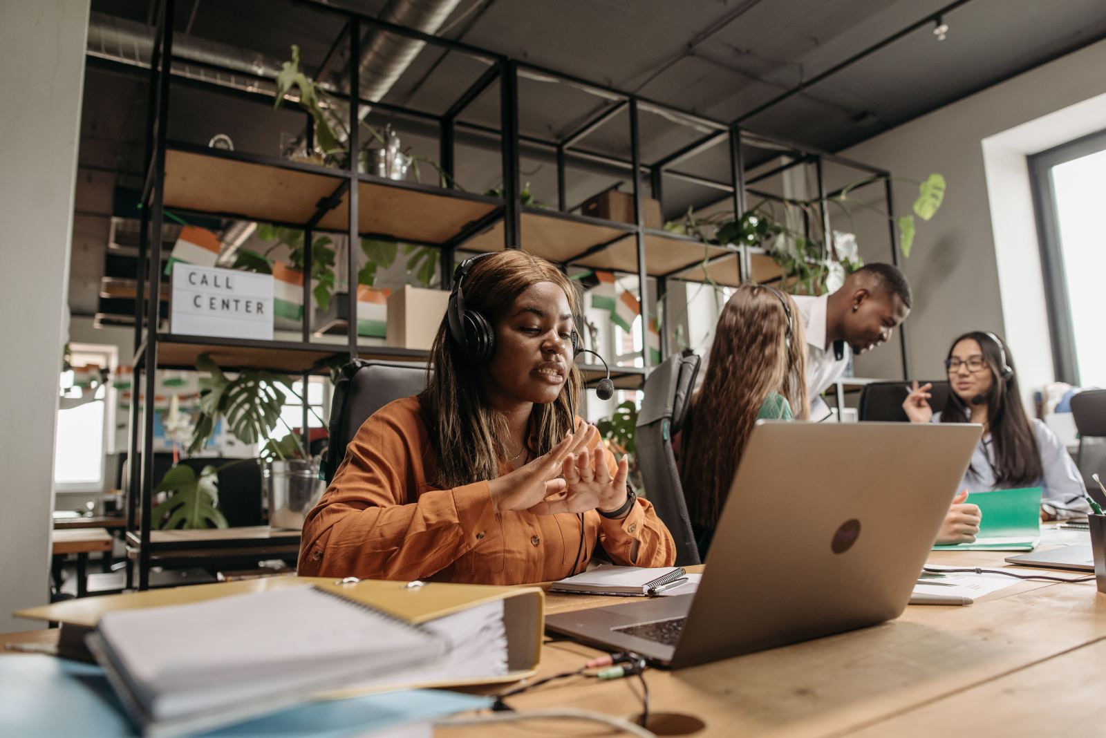 Call answering agent working at a laptop with a Call Center sign visible on a shelf behind her