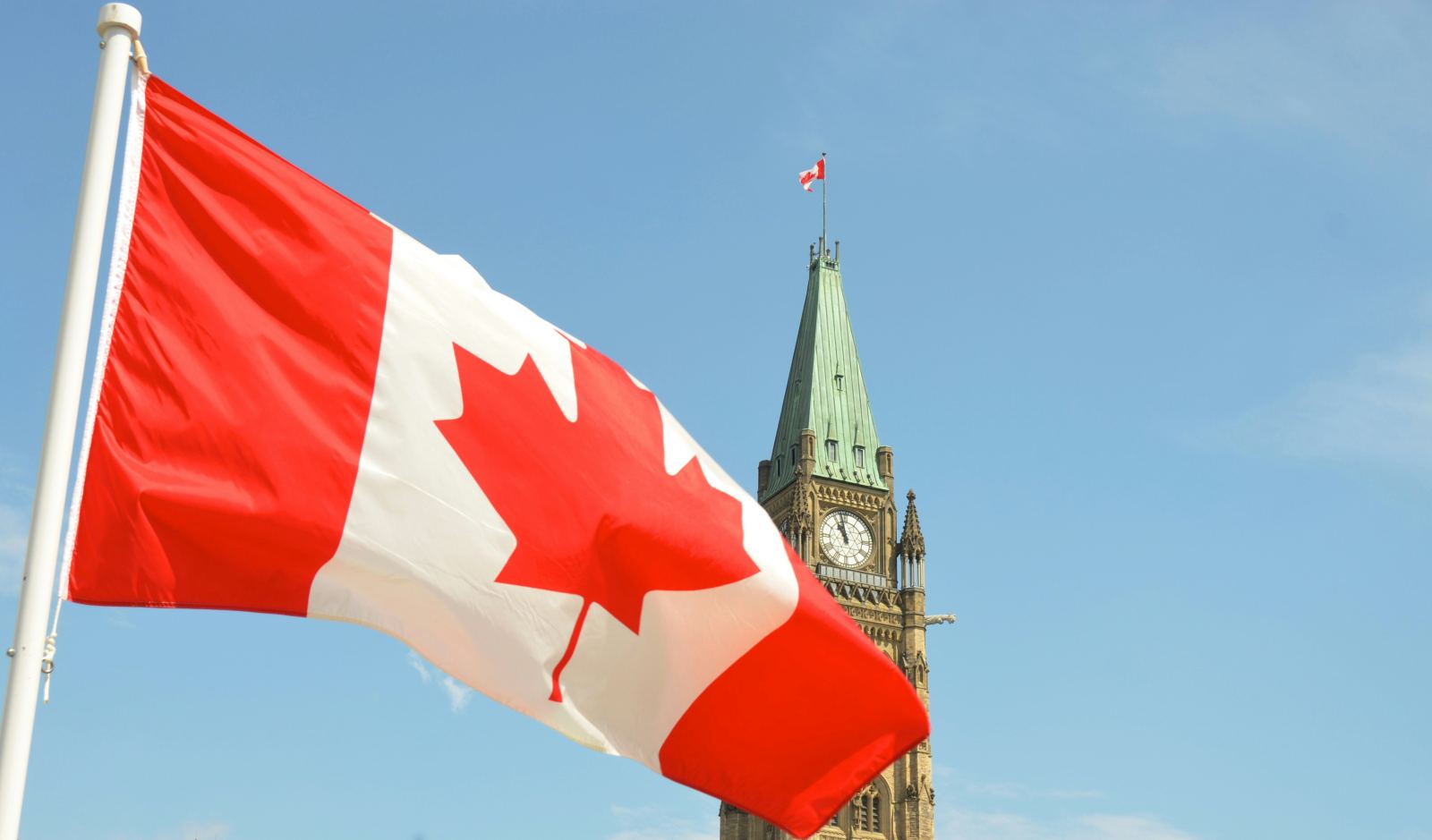 Canadian flag waving in front of the Peace Tower on Parliament Hill