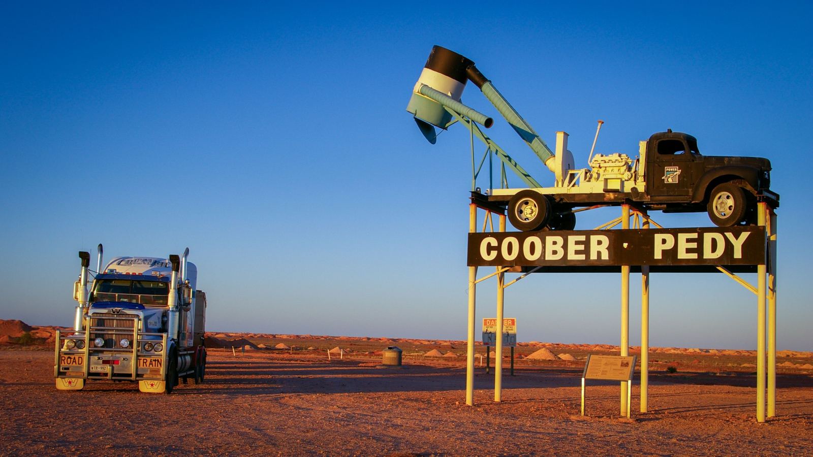 Road train truck parked beside a Coober Pedy roadside sign in the Australian outback