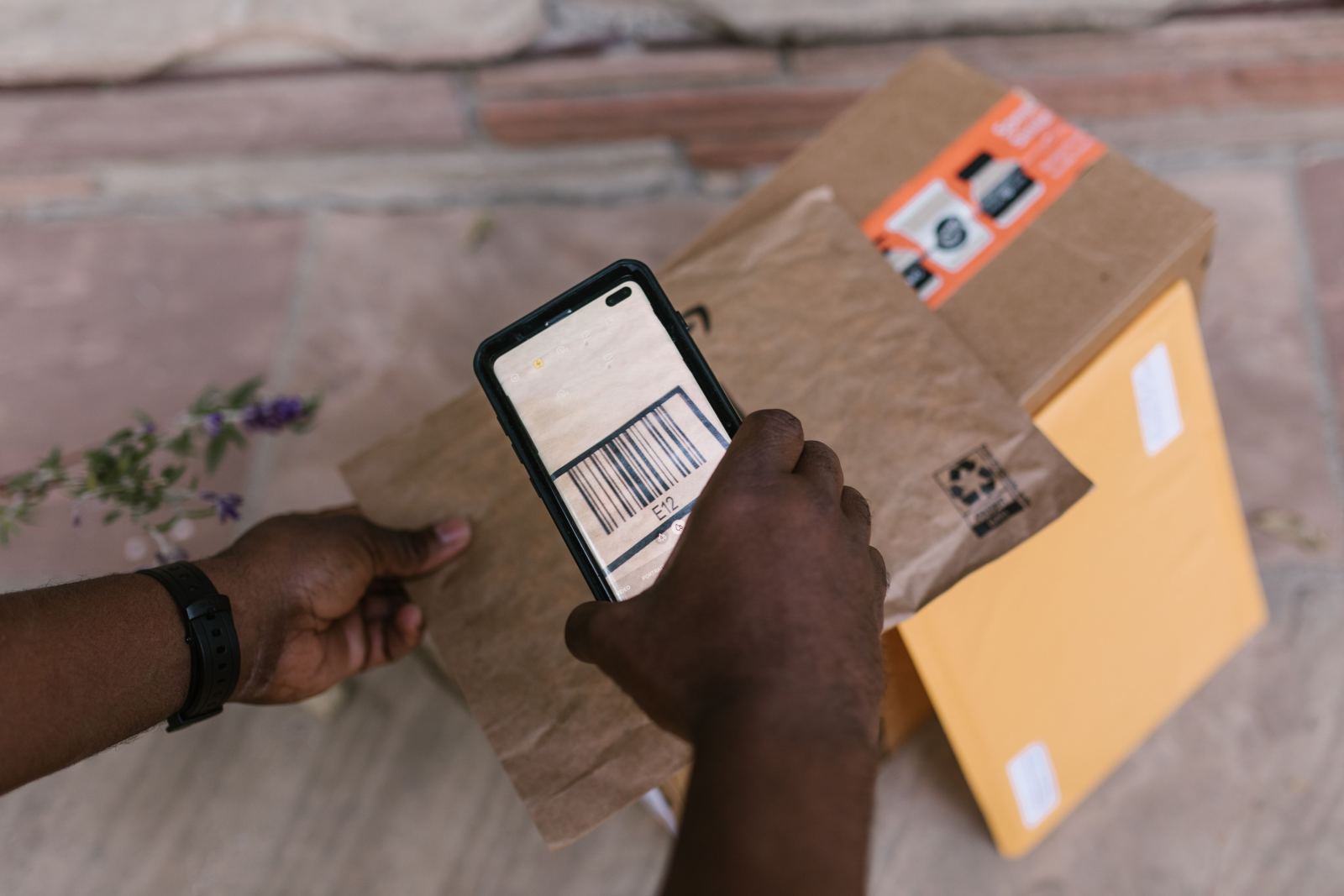 Hand using a smartphone to scan a barcode on a delivery package