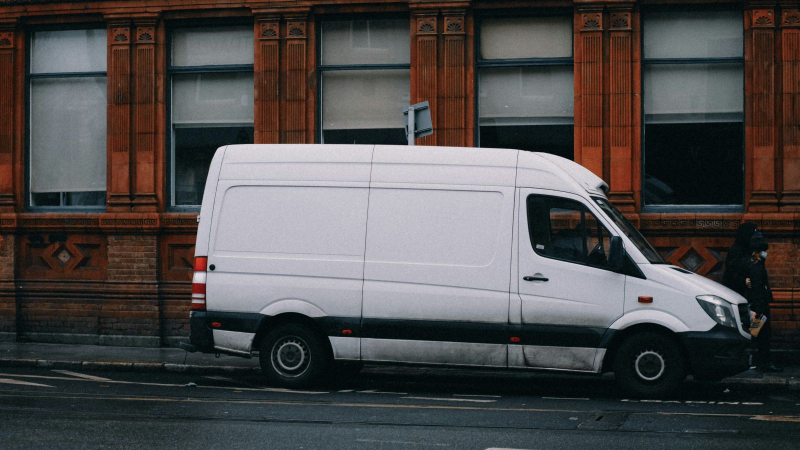 White delivery van parked along a brick-fronted city street