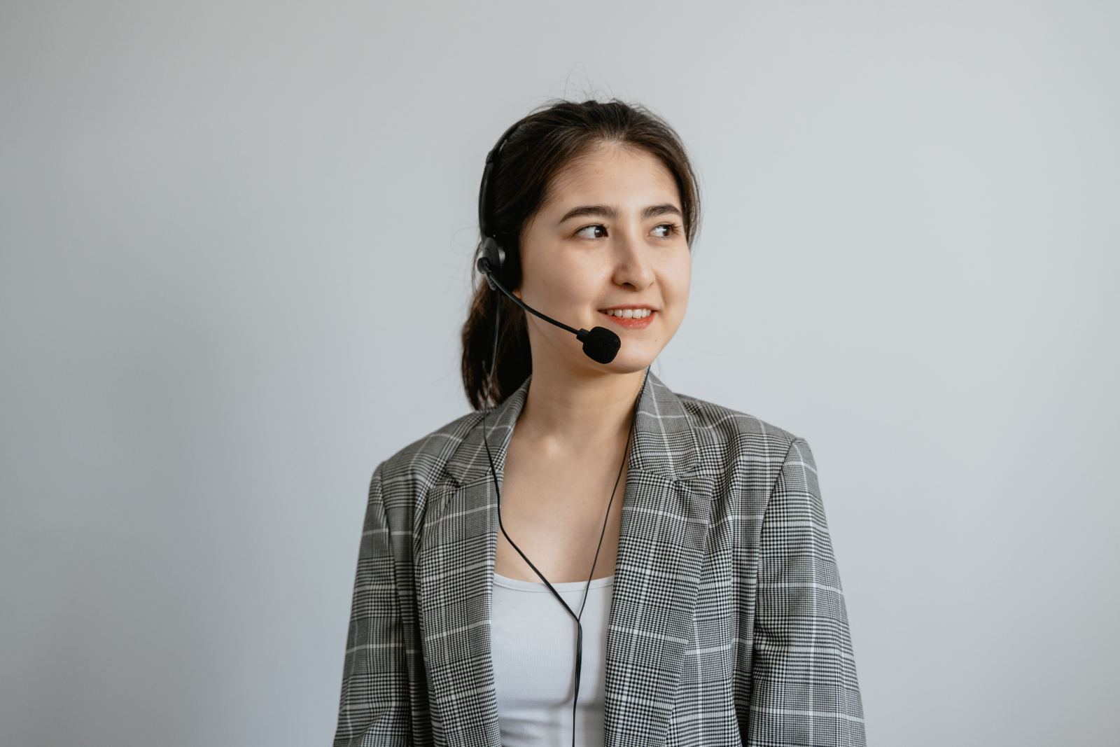 Smiling call center agent wearing a headset against a plain background
