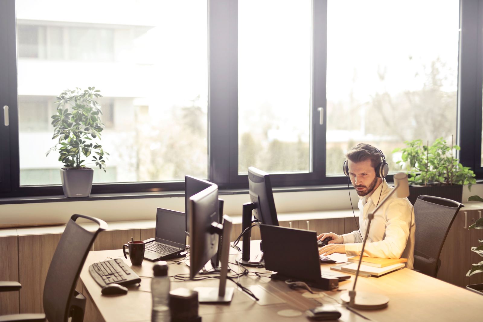 Dispatcher wearing a headset working at a desk with multiple monitors and a laptop