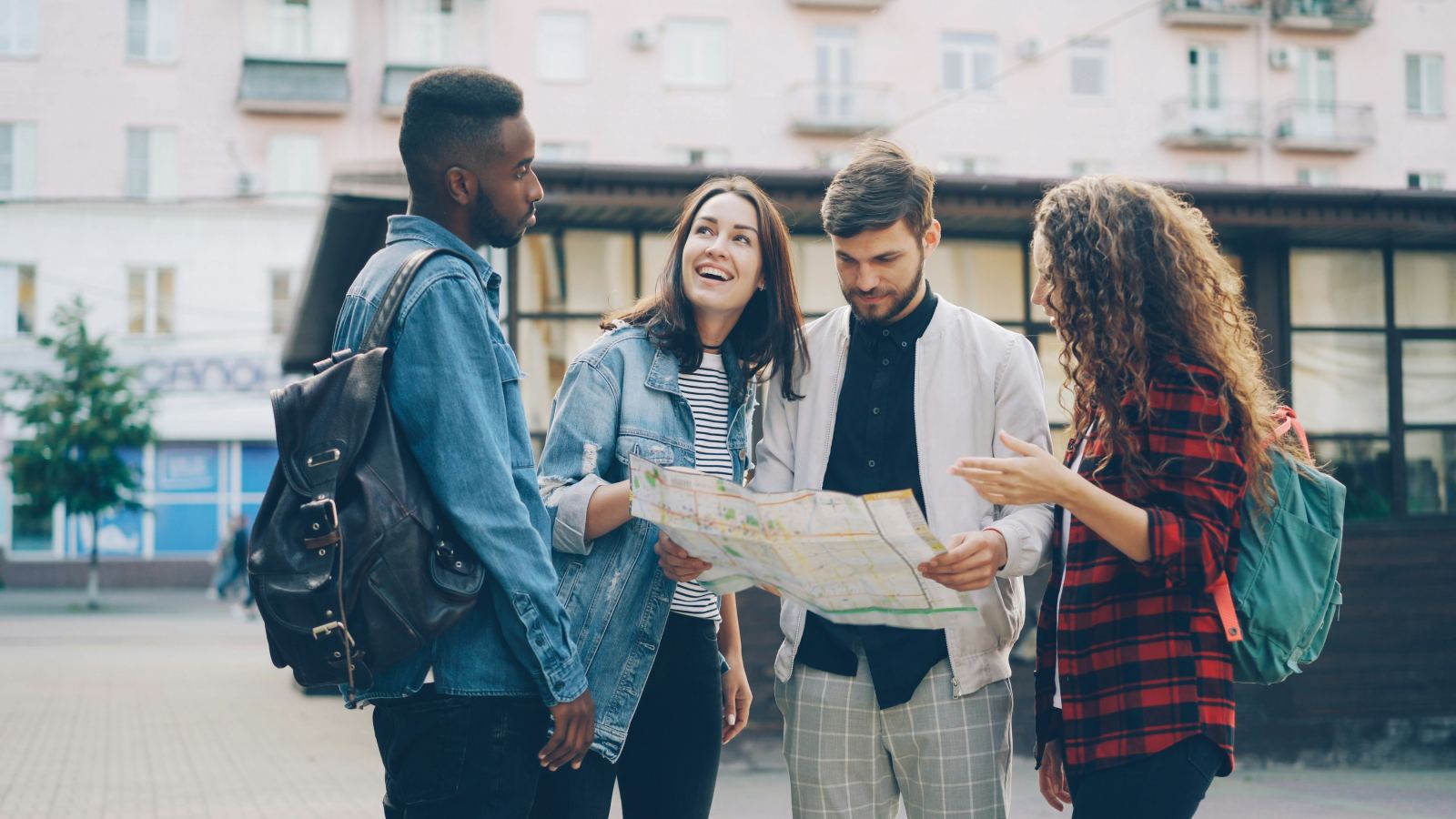 Group of friends studying a paper city map together on the street