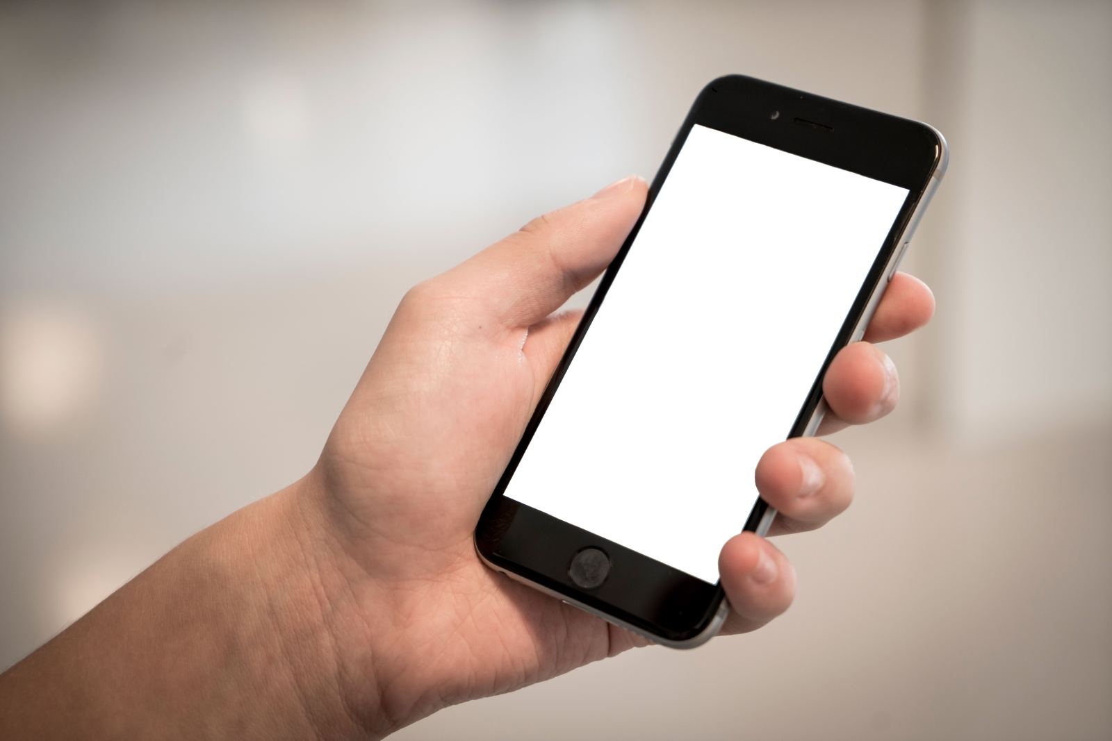 Close-up of a hand holding a smartphone with a blank white screen