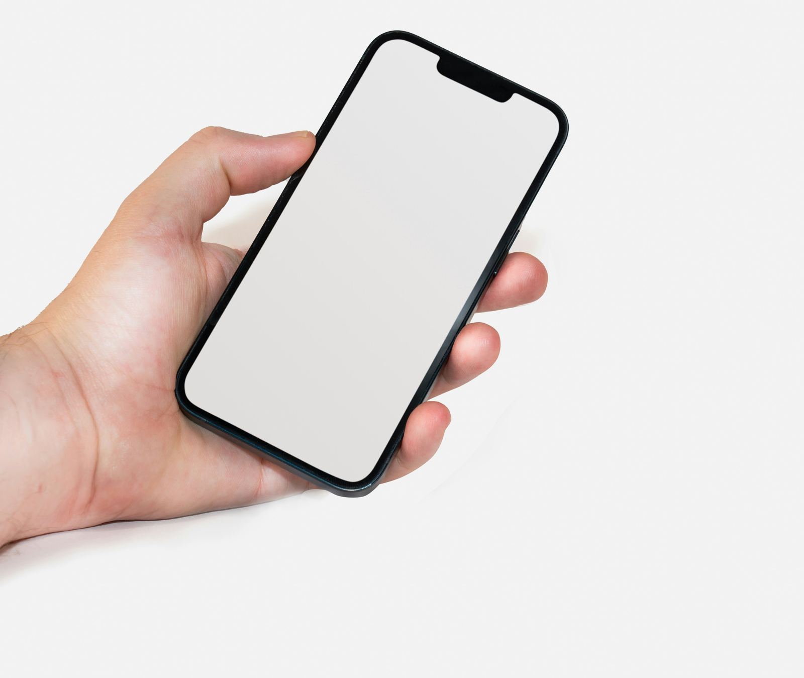 Hand holding a smartphone with a blank screen against a blurred grey office background