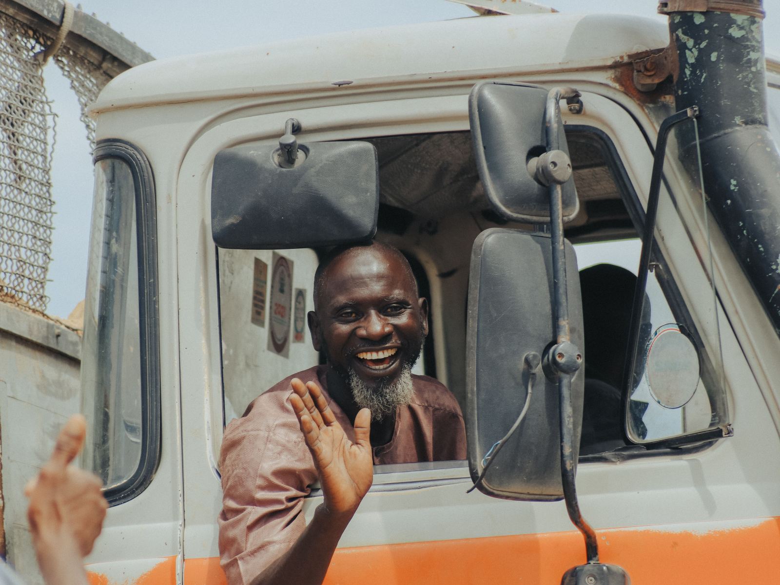 Cheerful truck driver waving and smiling from his vehicle window