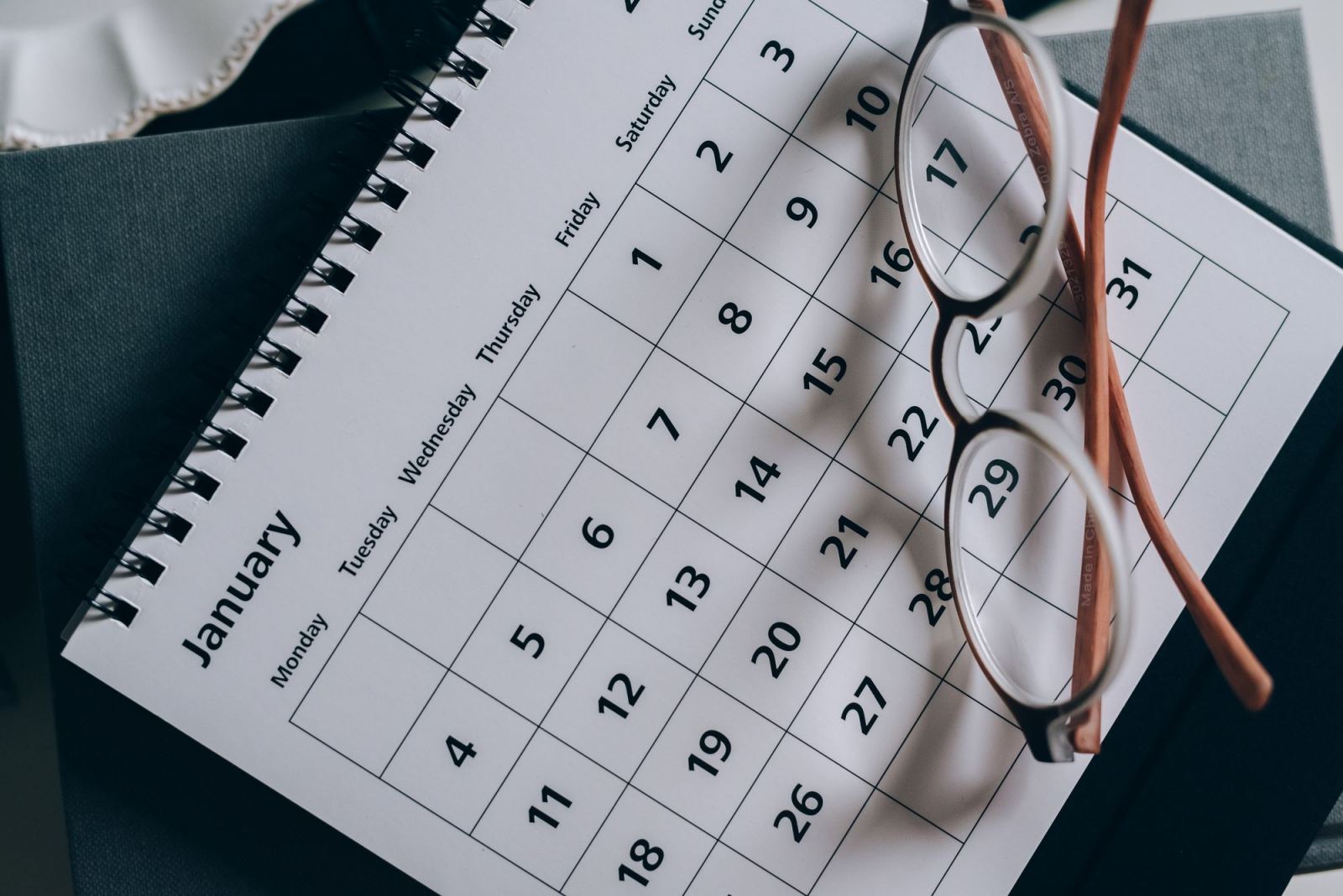 Reading glasses resting on an open January calendar
