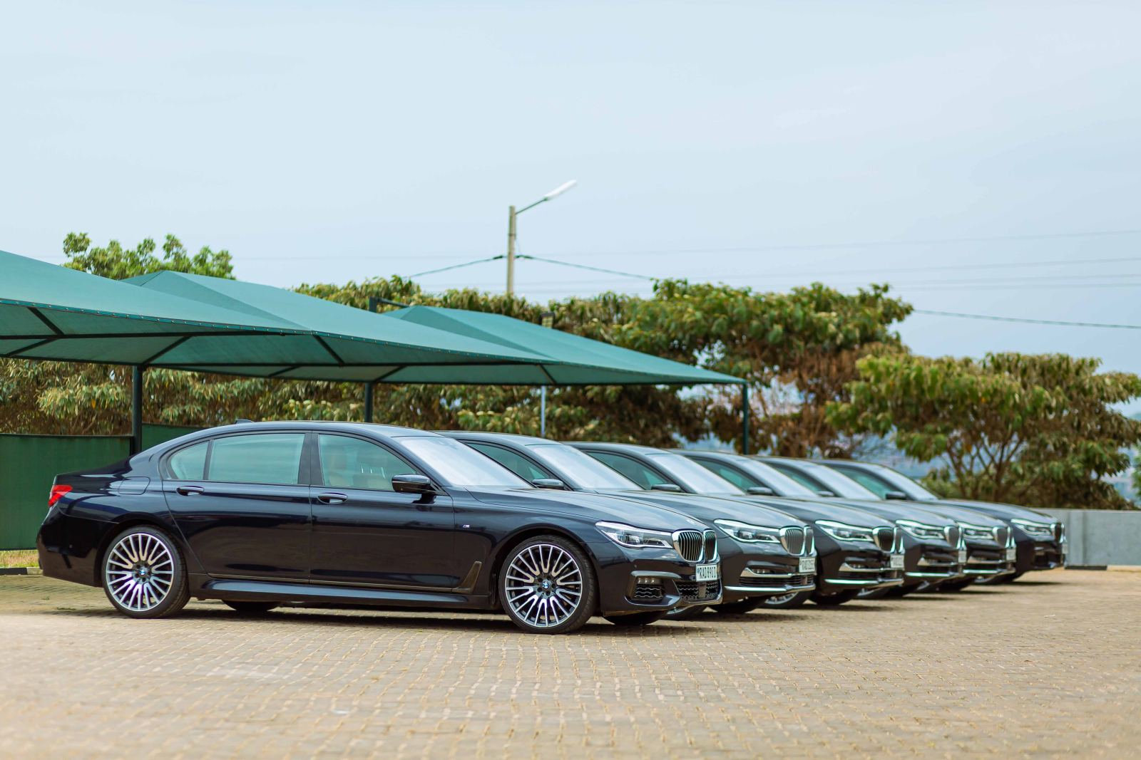 Row of matching black luxury sedans parked under a canopy