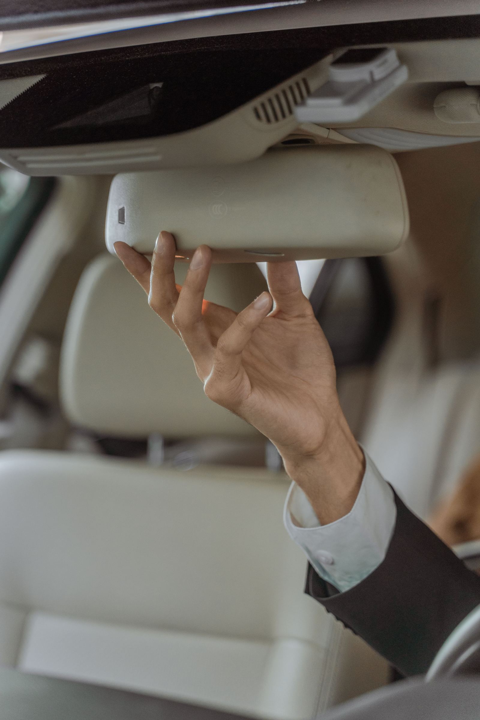 Close-up of a hand adjusting the rearview mirror inside a luxury car
