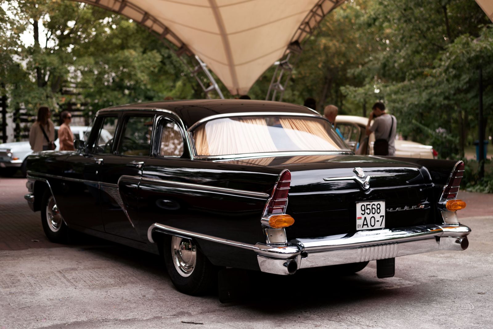 Vintage black Chaika luxury sedan parked at an outdoor event