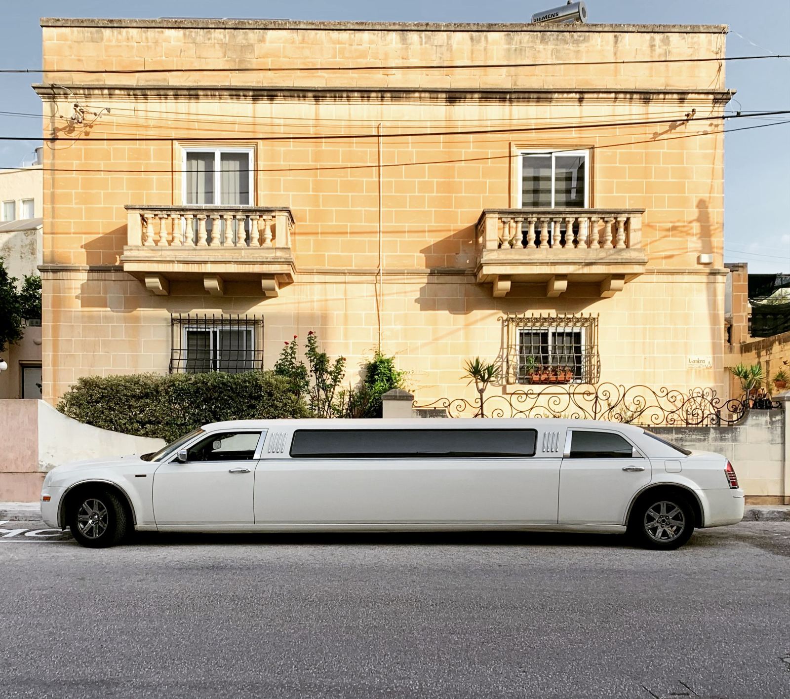 White stretch limousine parked in front of a townhouse on a quiet street