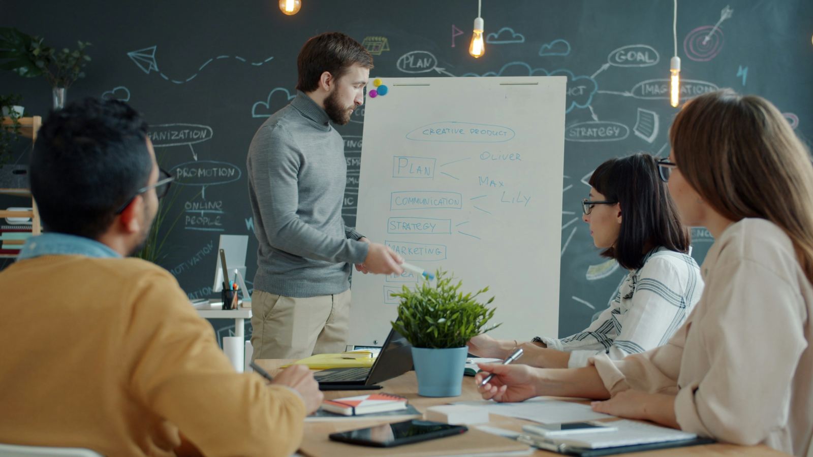 Man presenting a strategy and goals flip chart to colleagues