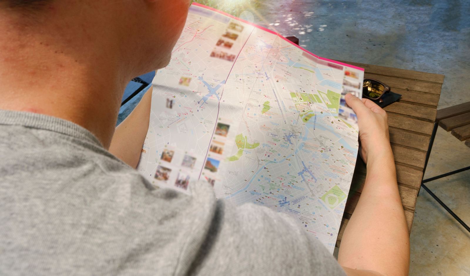 Man reading a folded tourist city map at an outdoor table