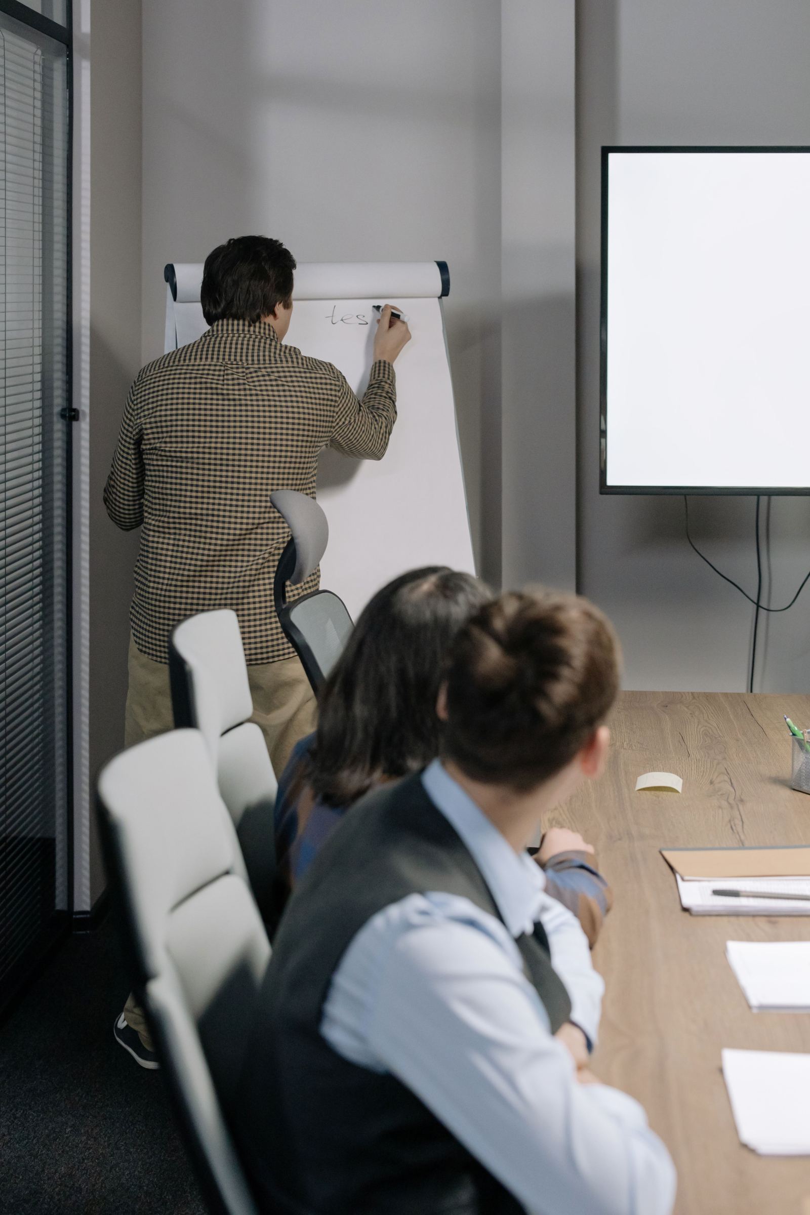 Man writing on a flip chart in front of colleagues in a conference room