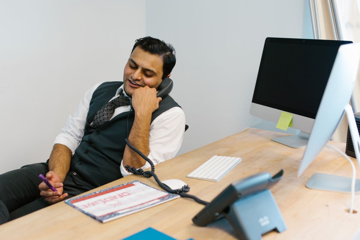 Dispatcher on a phone call at an office desk, coordinating NEMT trip scheduling