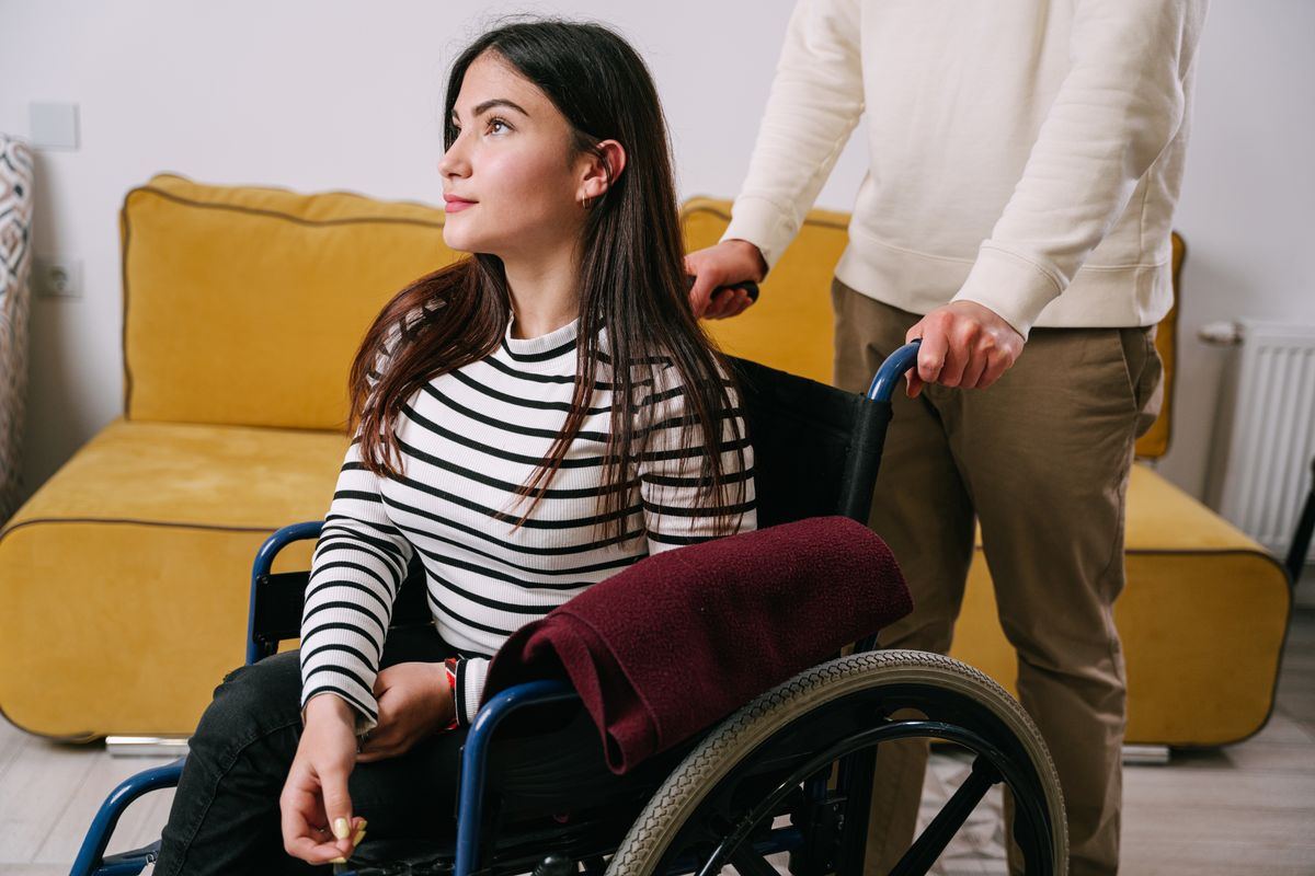 A person being assisted in a wheelchair indoors, representing patient transport booking and call handling