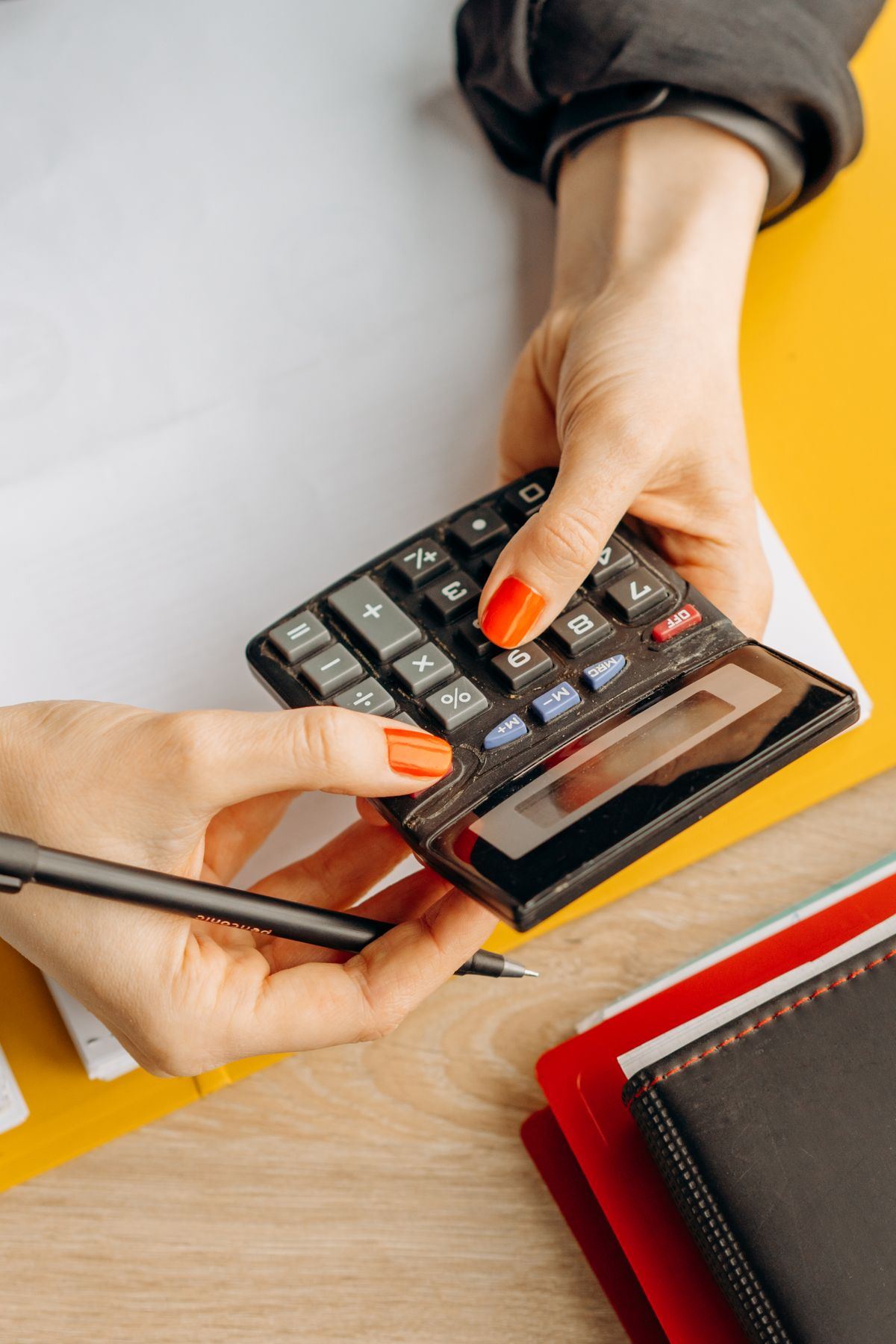 Hands using a calculator at a desk, representing NEMT billing and claims follow-up