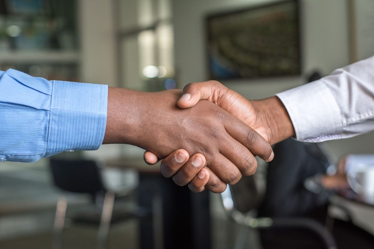 Two professionals shaking hands in an office, representing reliable after-hours NEMT coverage