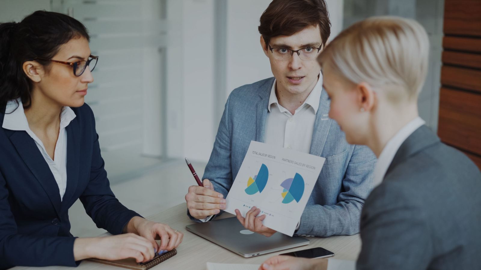 Colleagues reviewing sales charts together around an office table