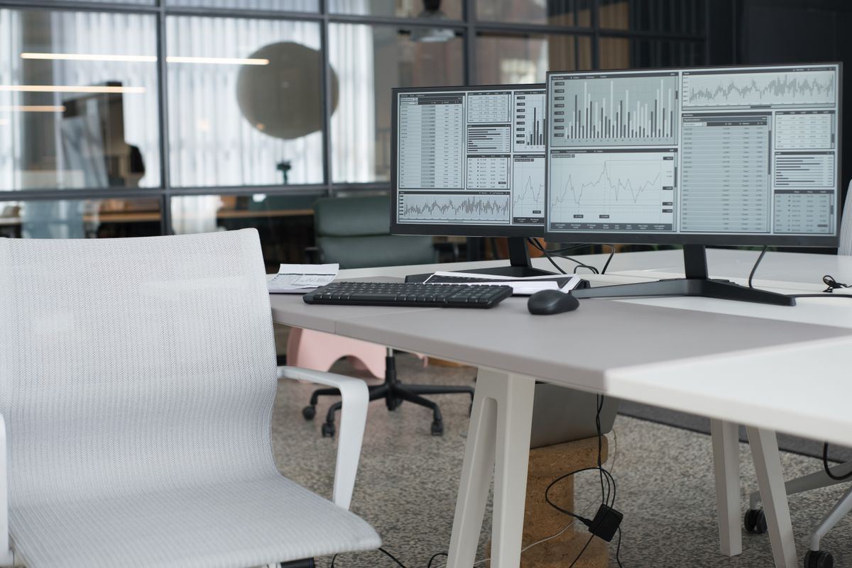 Dual office monitors displaying performance charts and data, representing NEMT on-time performance tracking