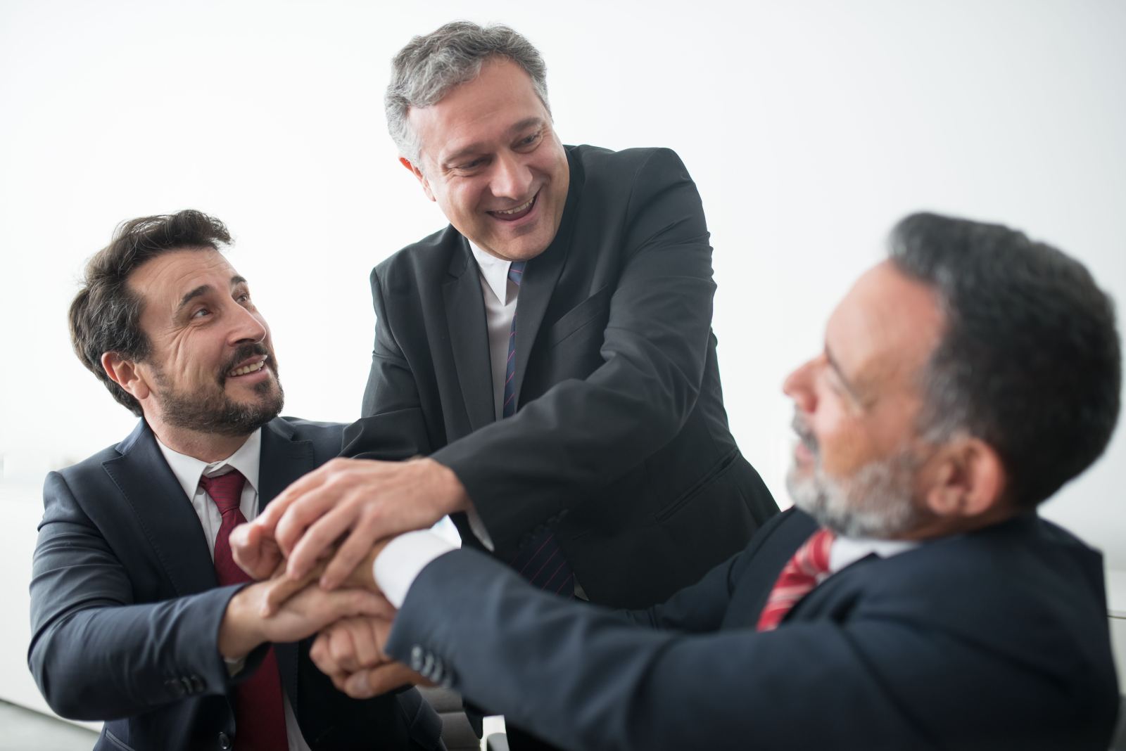 Three businessmen stacking hands together in a team huddle