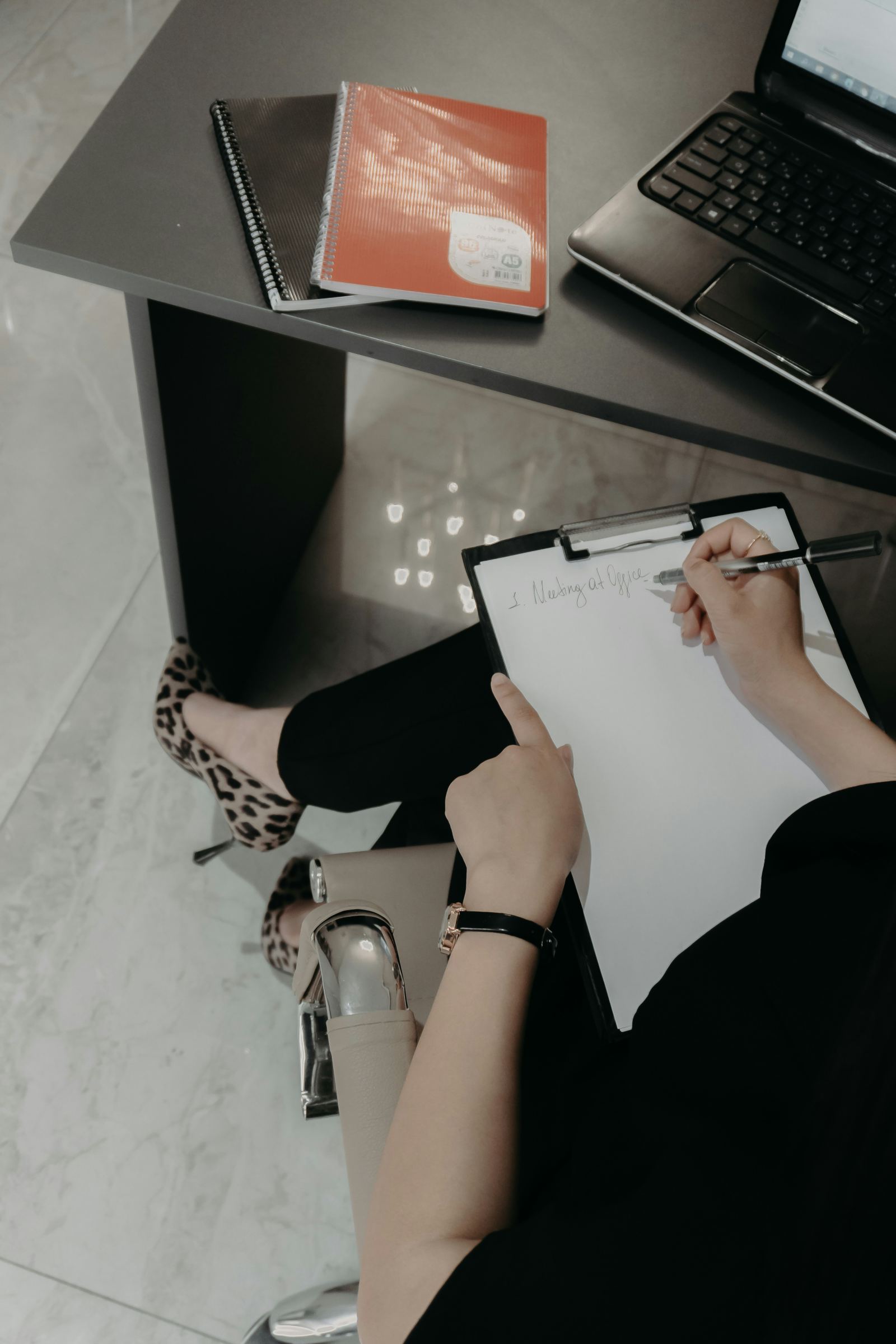 Overhead view of a person writing a checklist on a clipboard