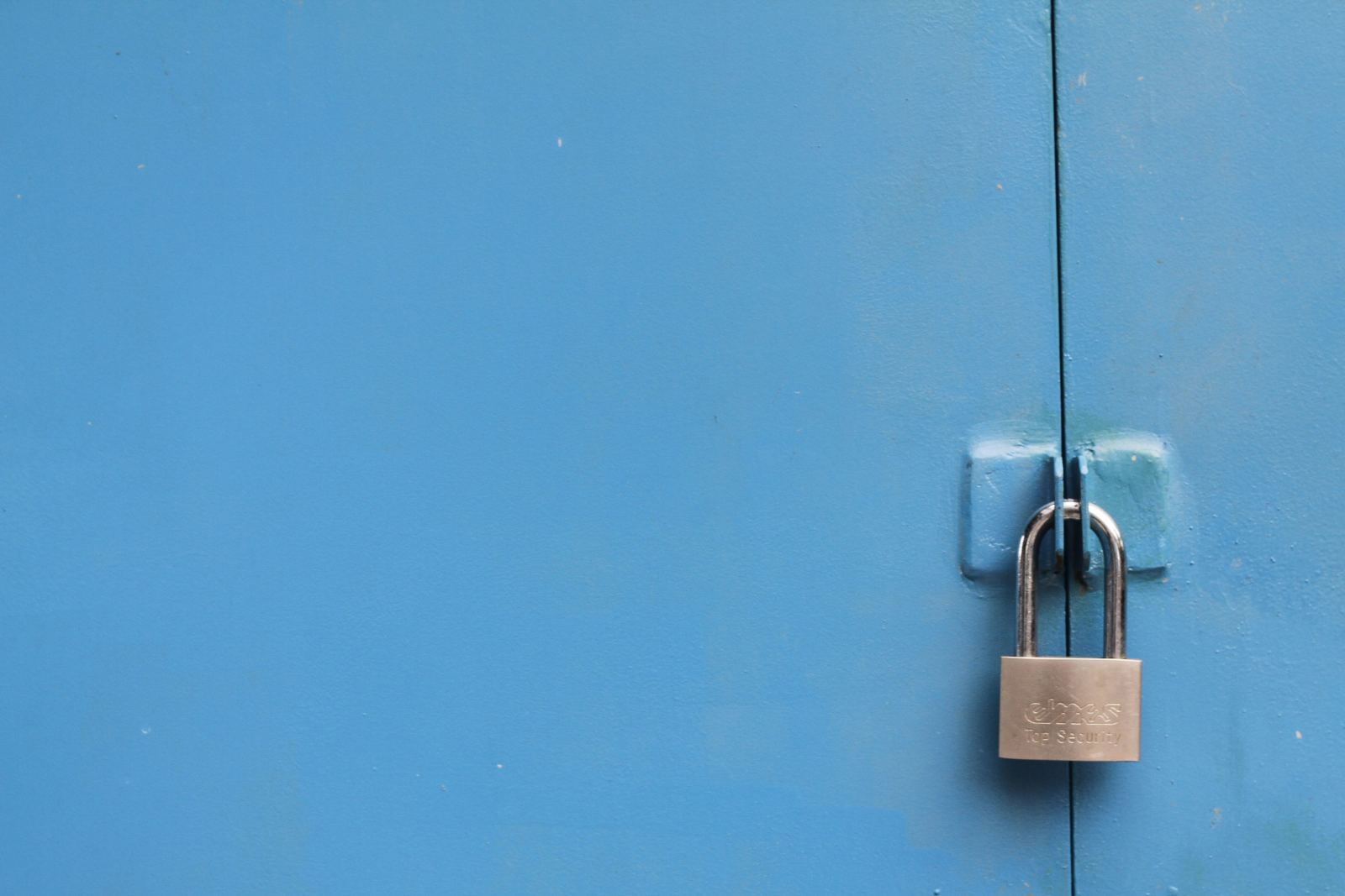 Silver padlock securing a blue metal door