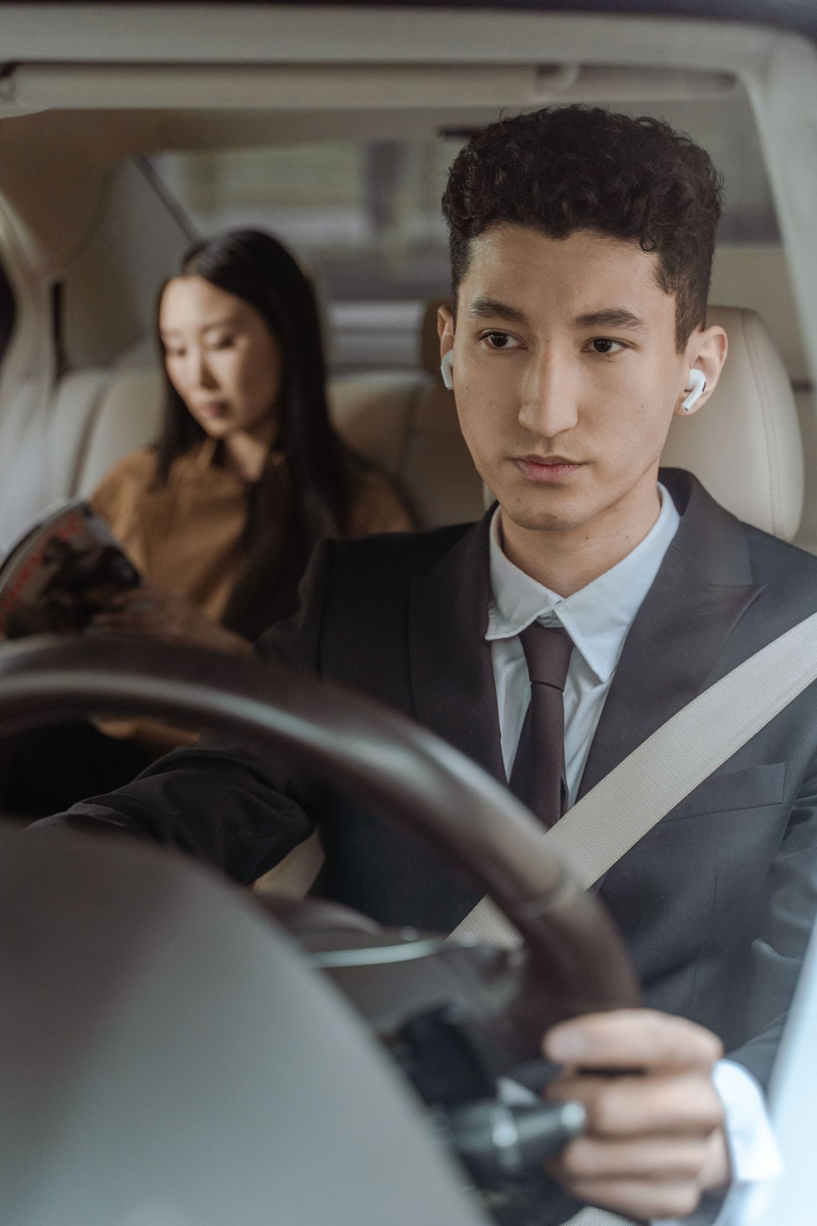 Businessman in a suit driving with a passenger seated behind him