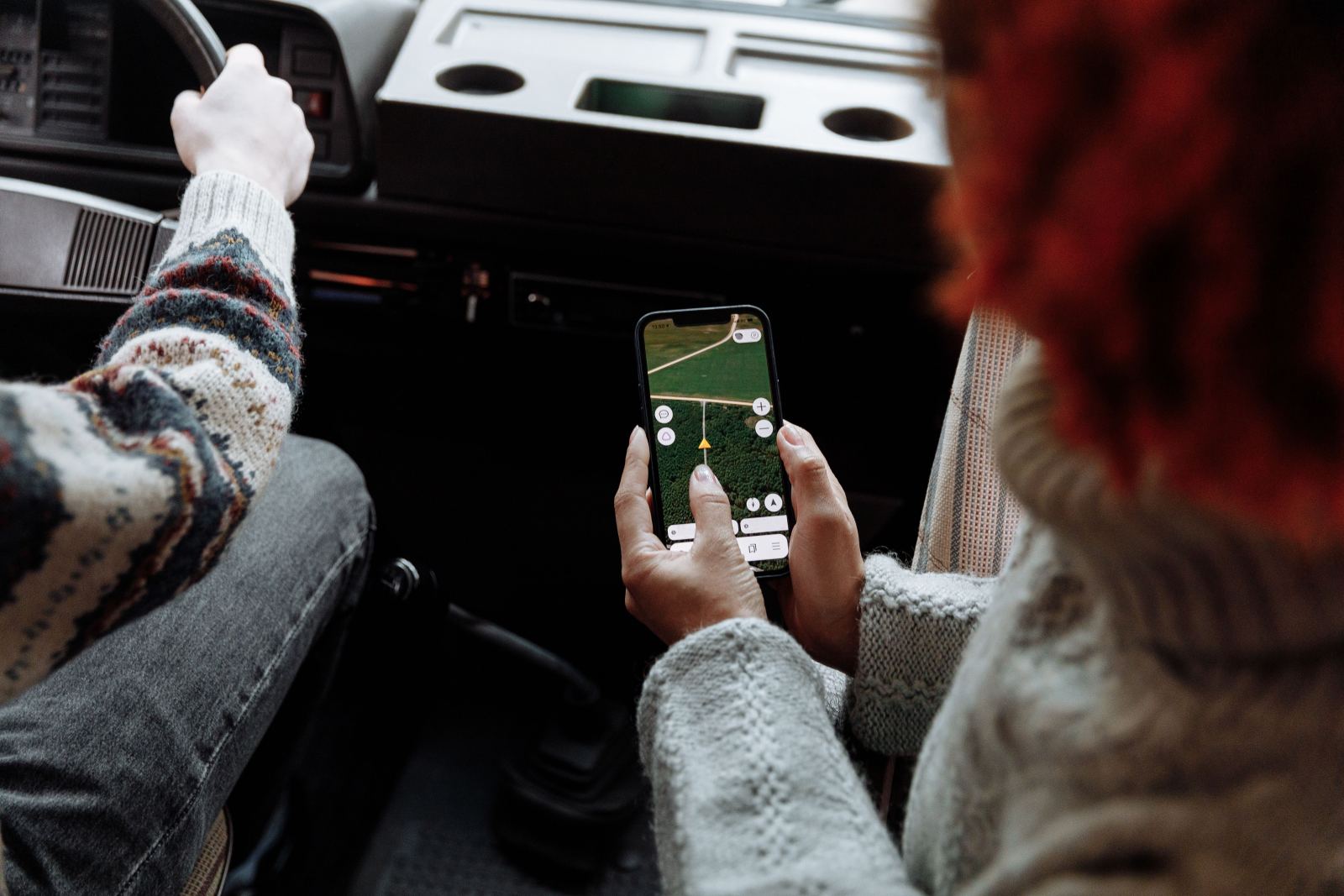 Passenger holding a phone with a navigation app open inside a vehicle
