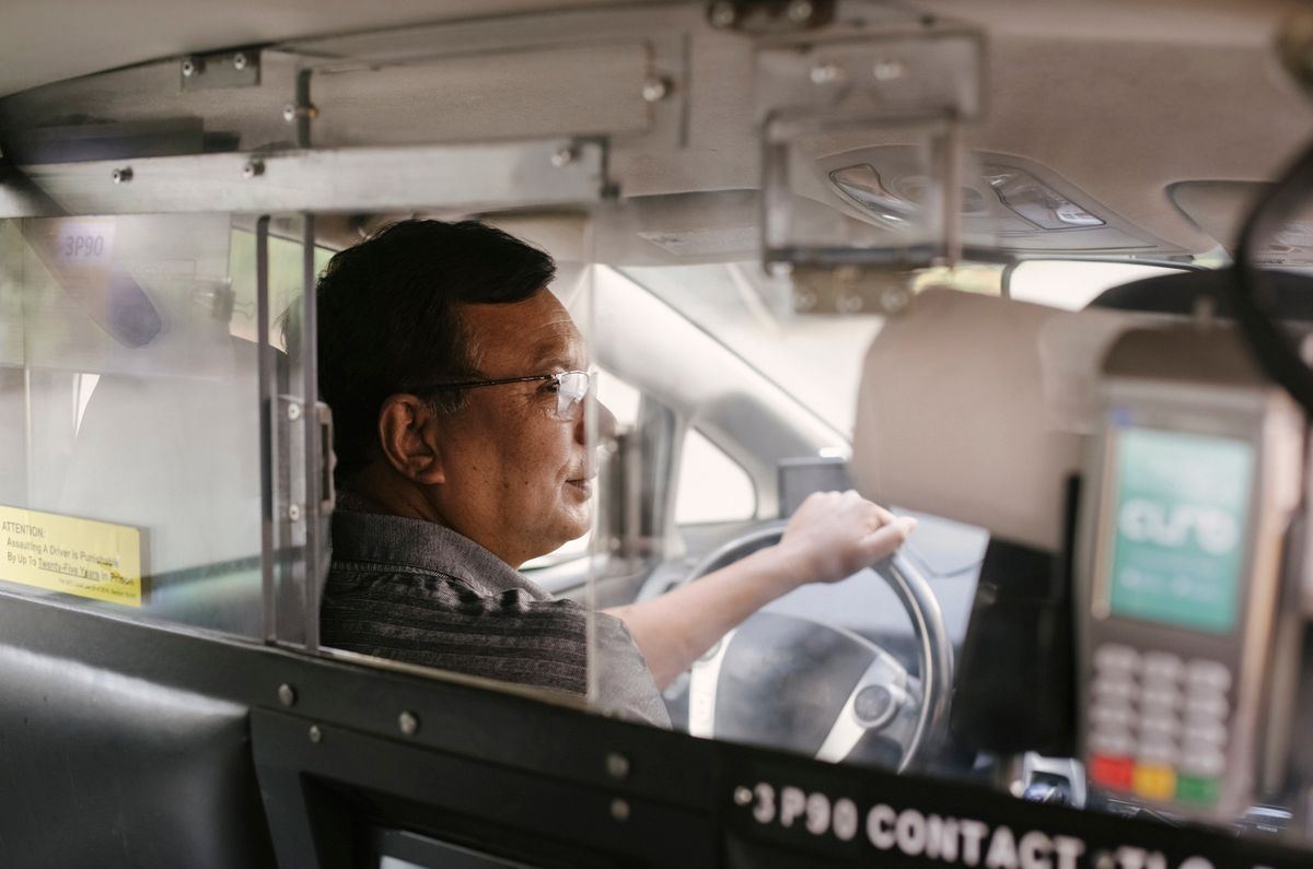 Taxi driver seen through the rearview mirror during a trip