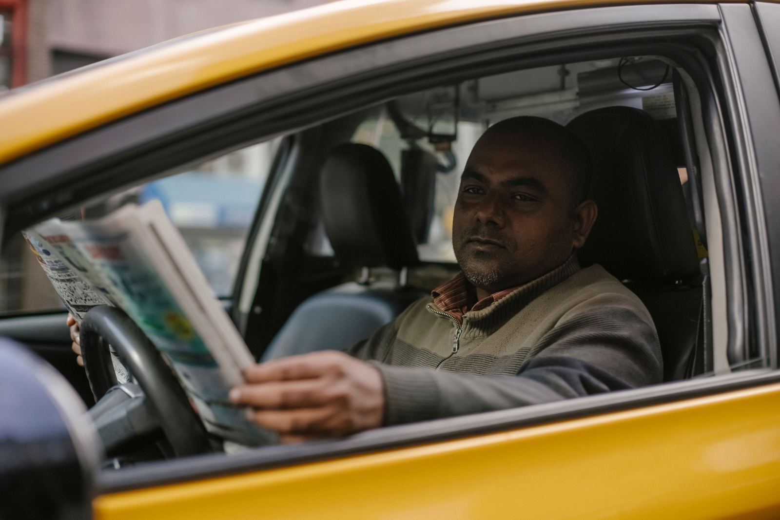 Taxi driver reading a newspaper during a break in his cab