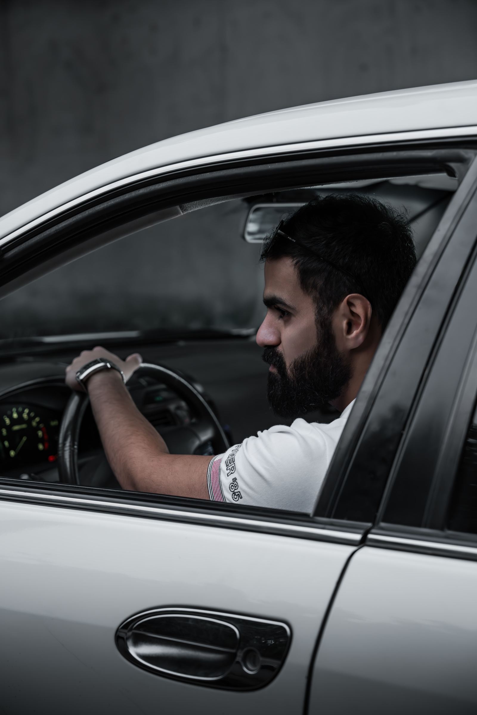 Bearded driver wearing sunglasses on his head driving through a garage