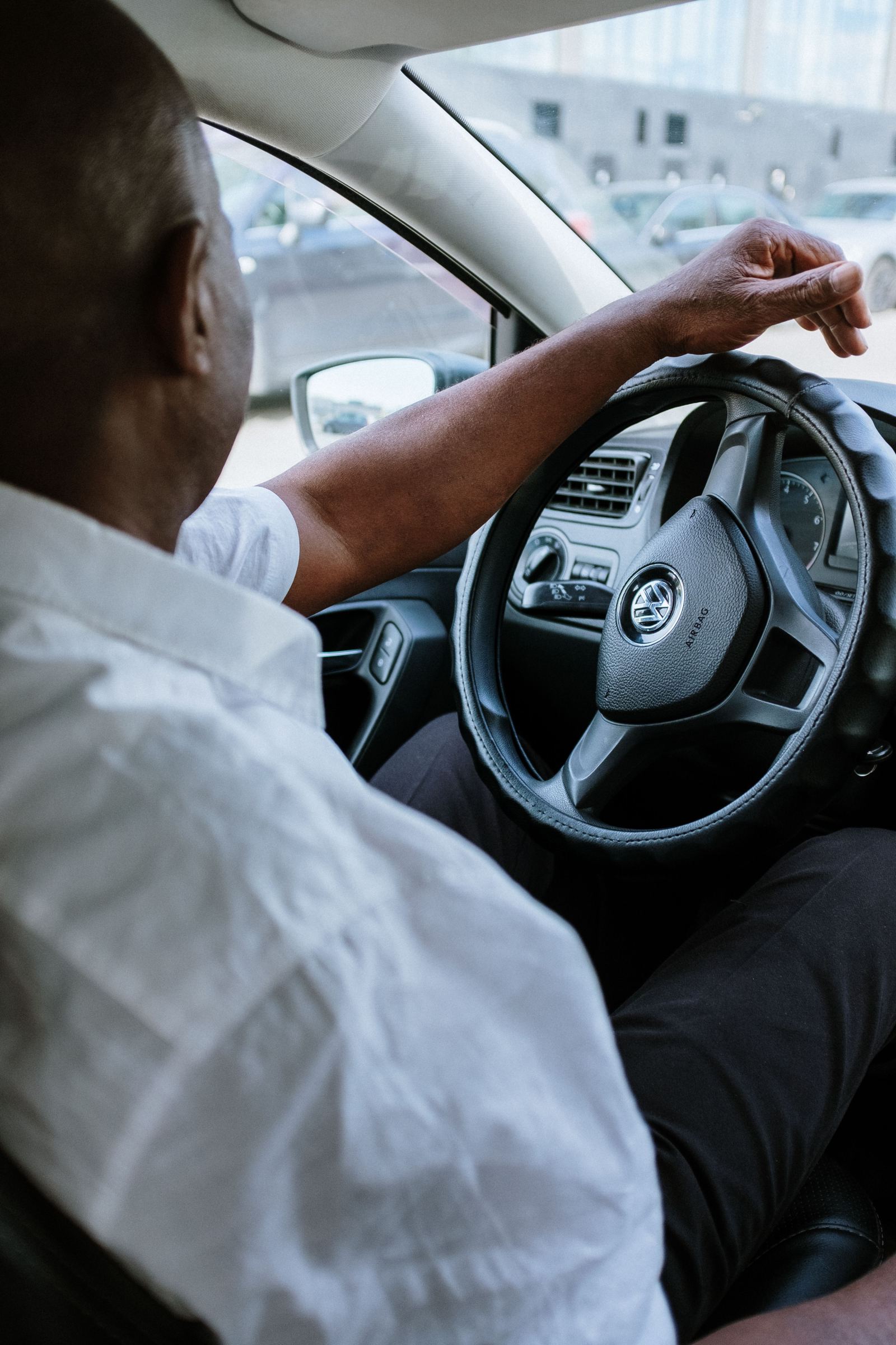 Driver with hand on a Volkswagen steering wheel in city traffic