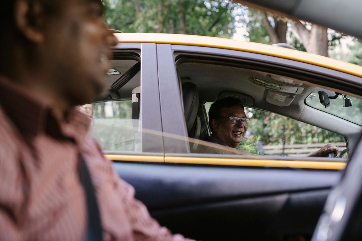 Two taxi drivers chatting between their cabs on a break