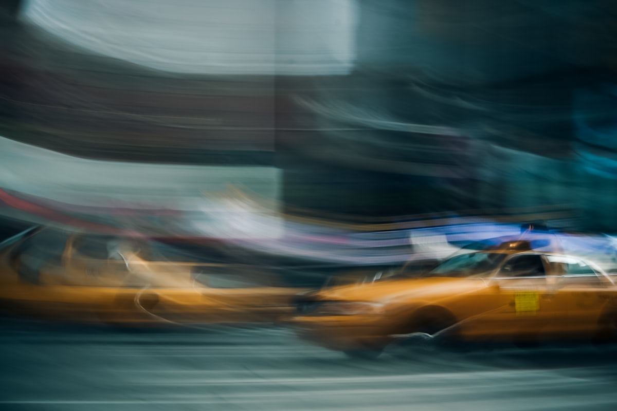 Motion-blurred yellow taxi cabs in a busy city street, representing 24/7 taxi dispatch outsourcing