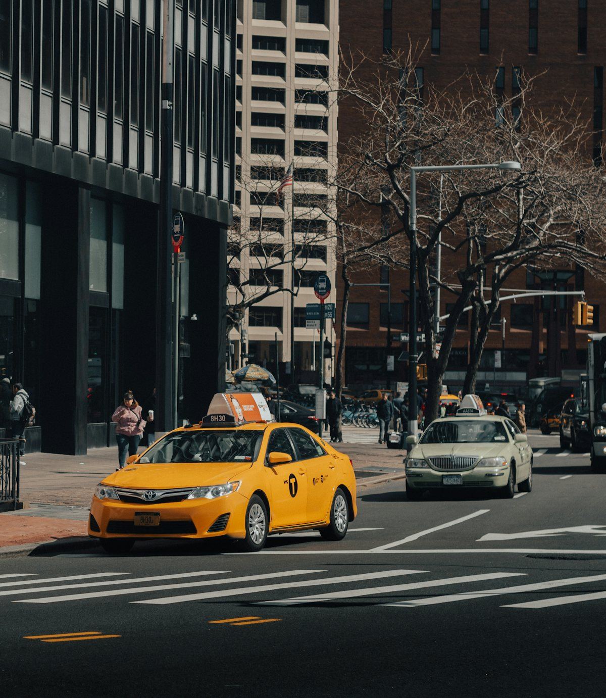 Yellow taxi and town car on a New York City street