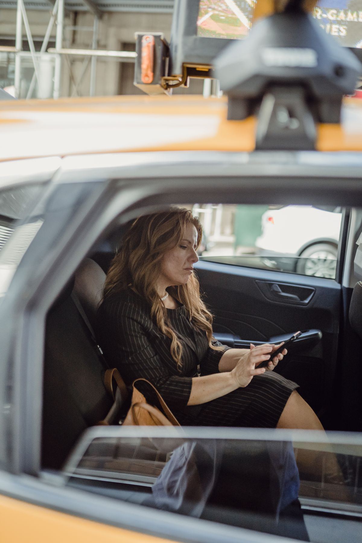 Passenger in the back seat of a taxi using her phone