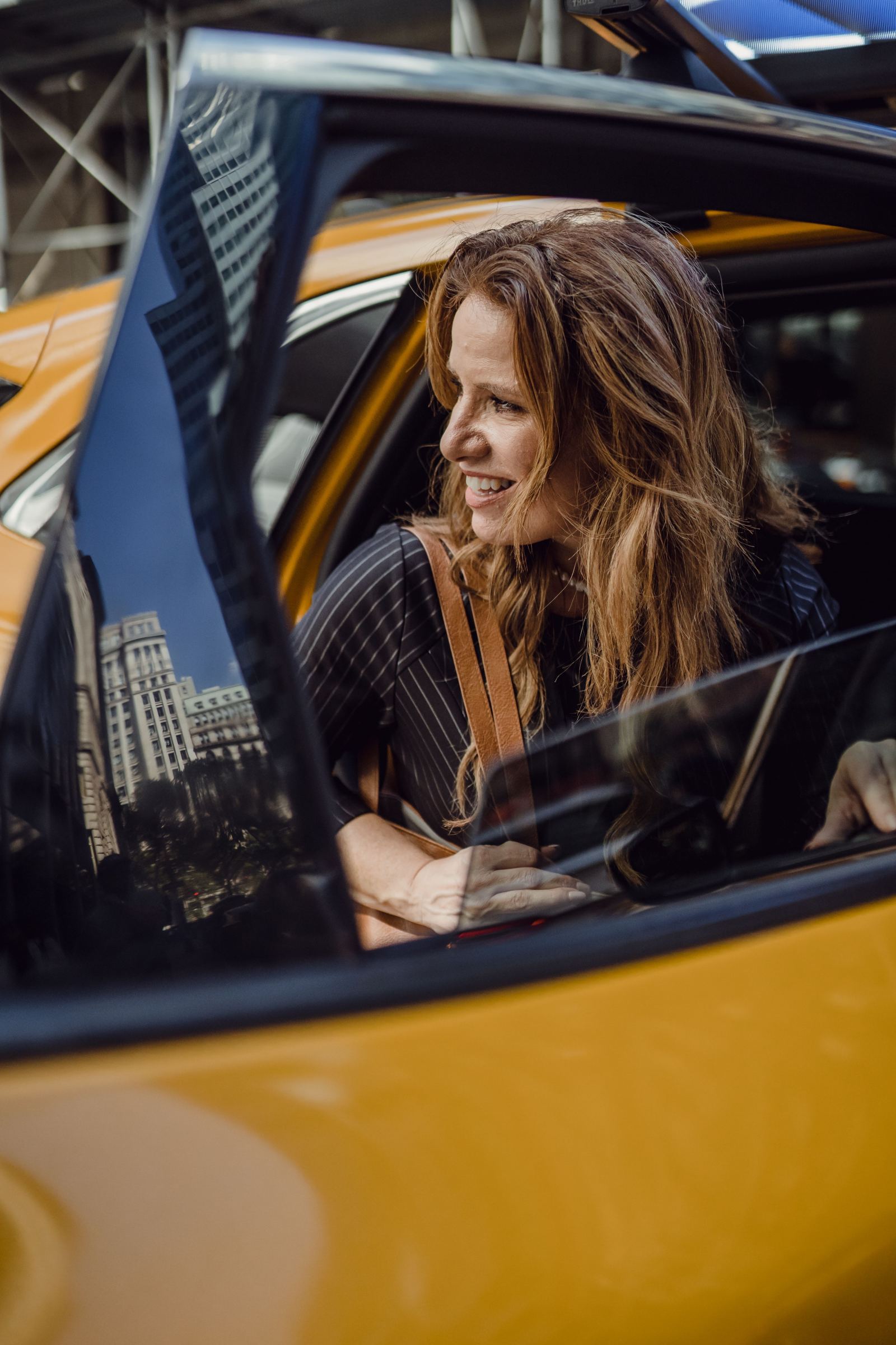 Smiling woman passenger seated in the back of a yellow taxi
