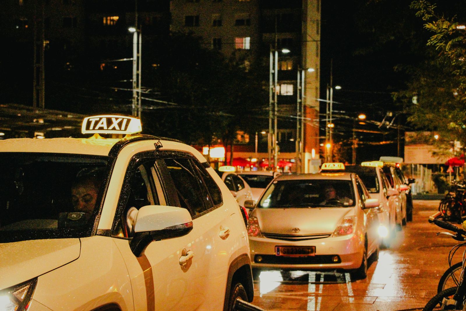 Row of taxis with illuminated roof signs queued at night