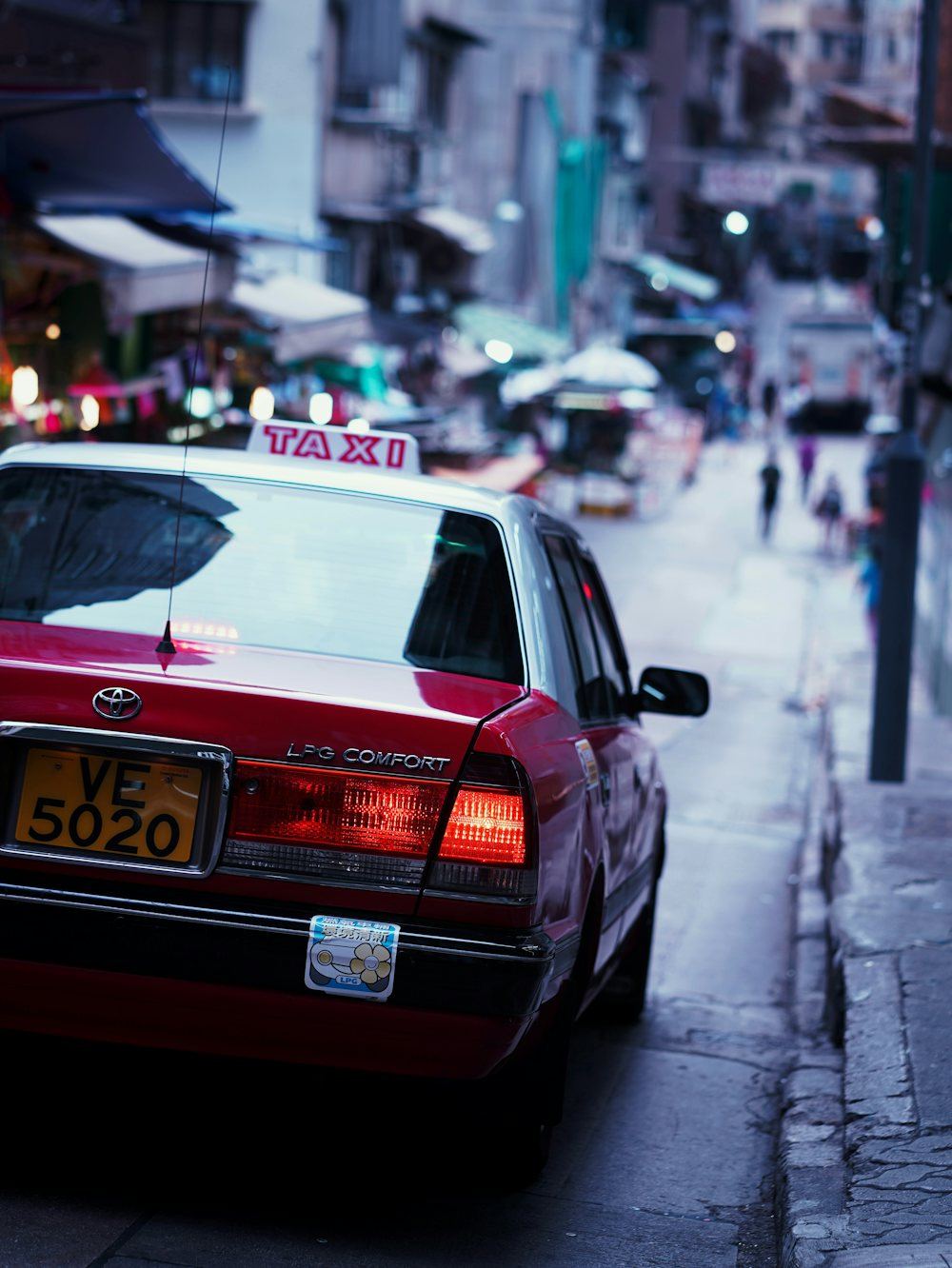 Close-up of a red taxi cab’s rear end with its illuminated roof light on a city street