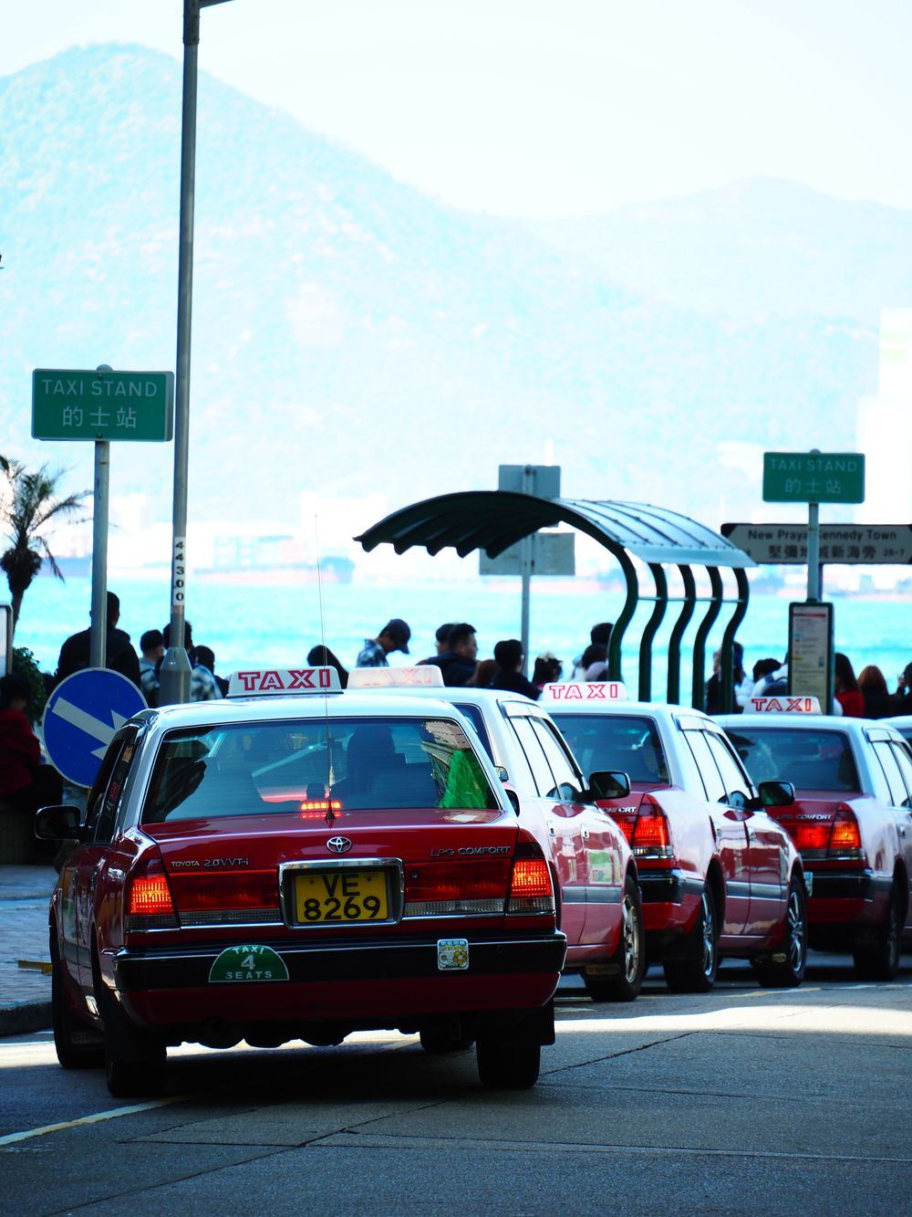Line of taxis queued at a waterfront taxi stand with mountains in the background
