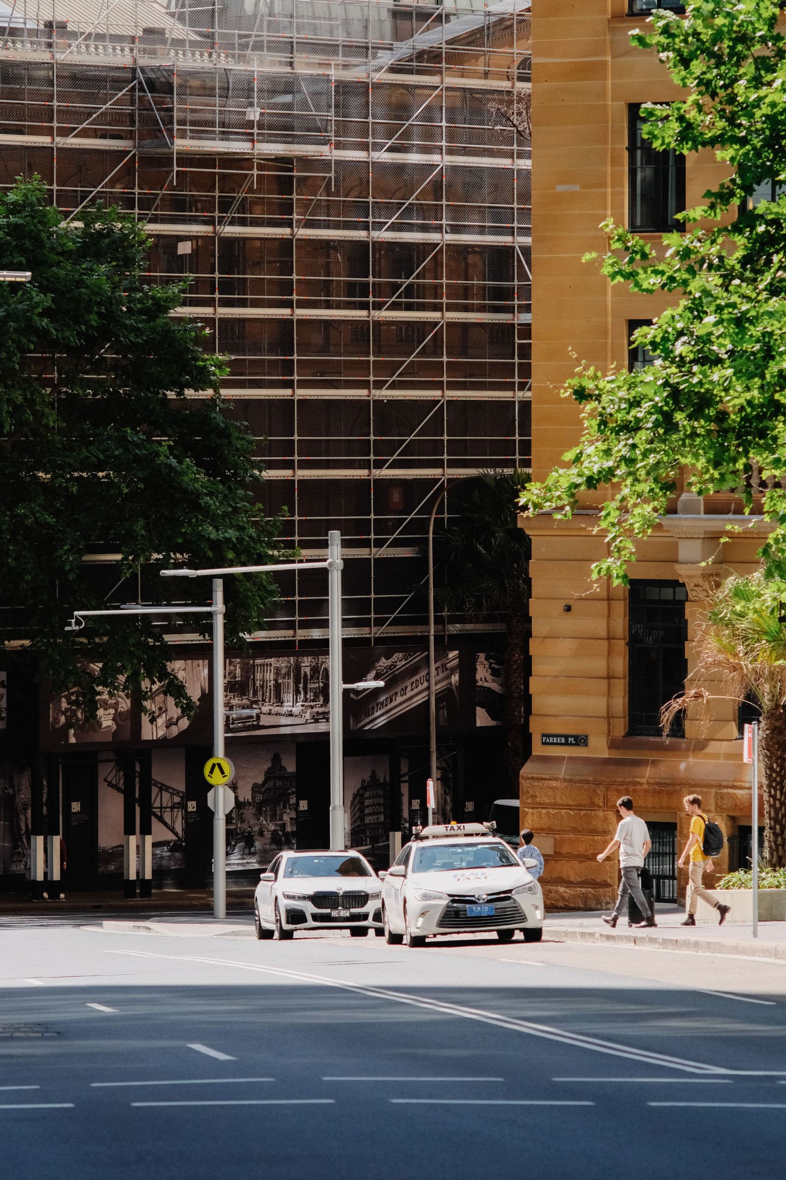 Taxis parked along a city street beside a scaffolded building