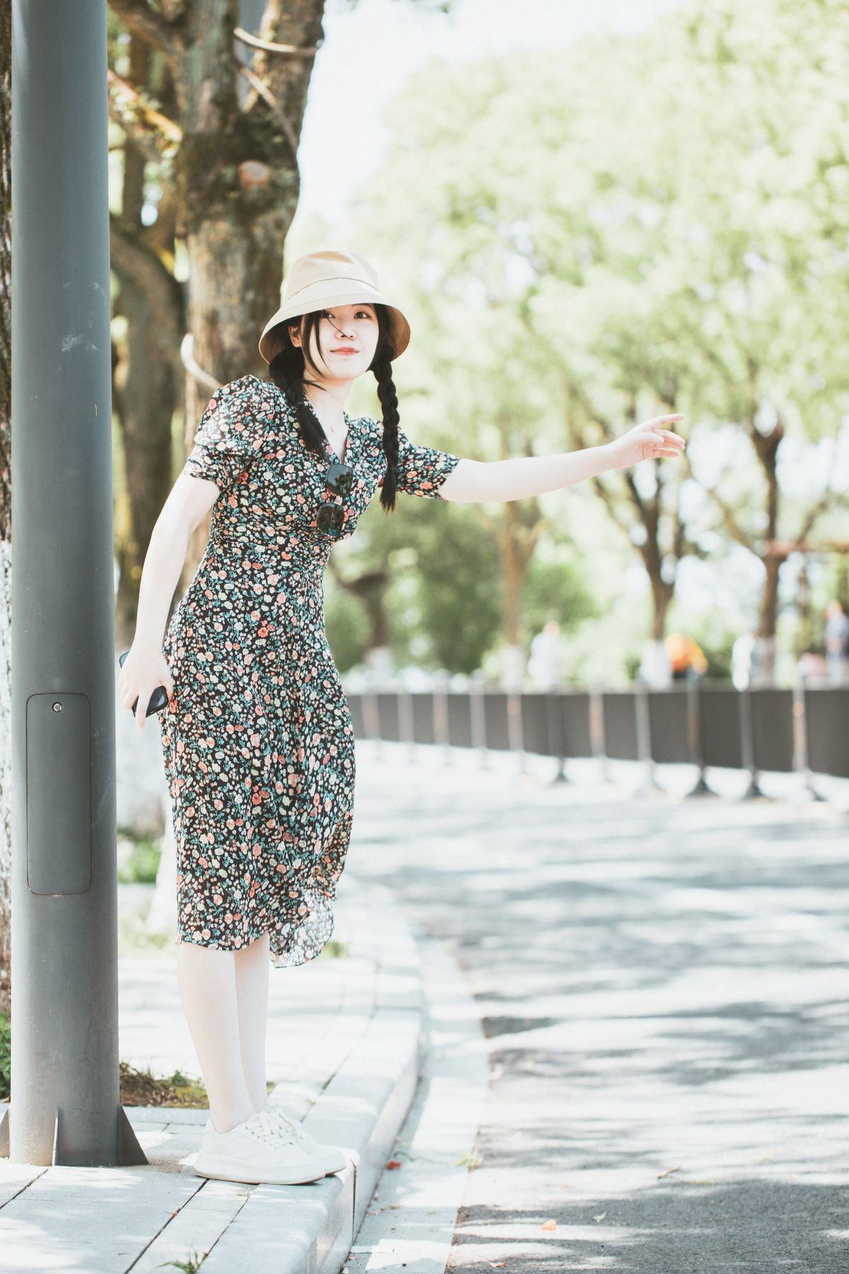 Woman standing on a sunny sidewalk hailing a cab