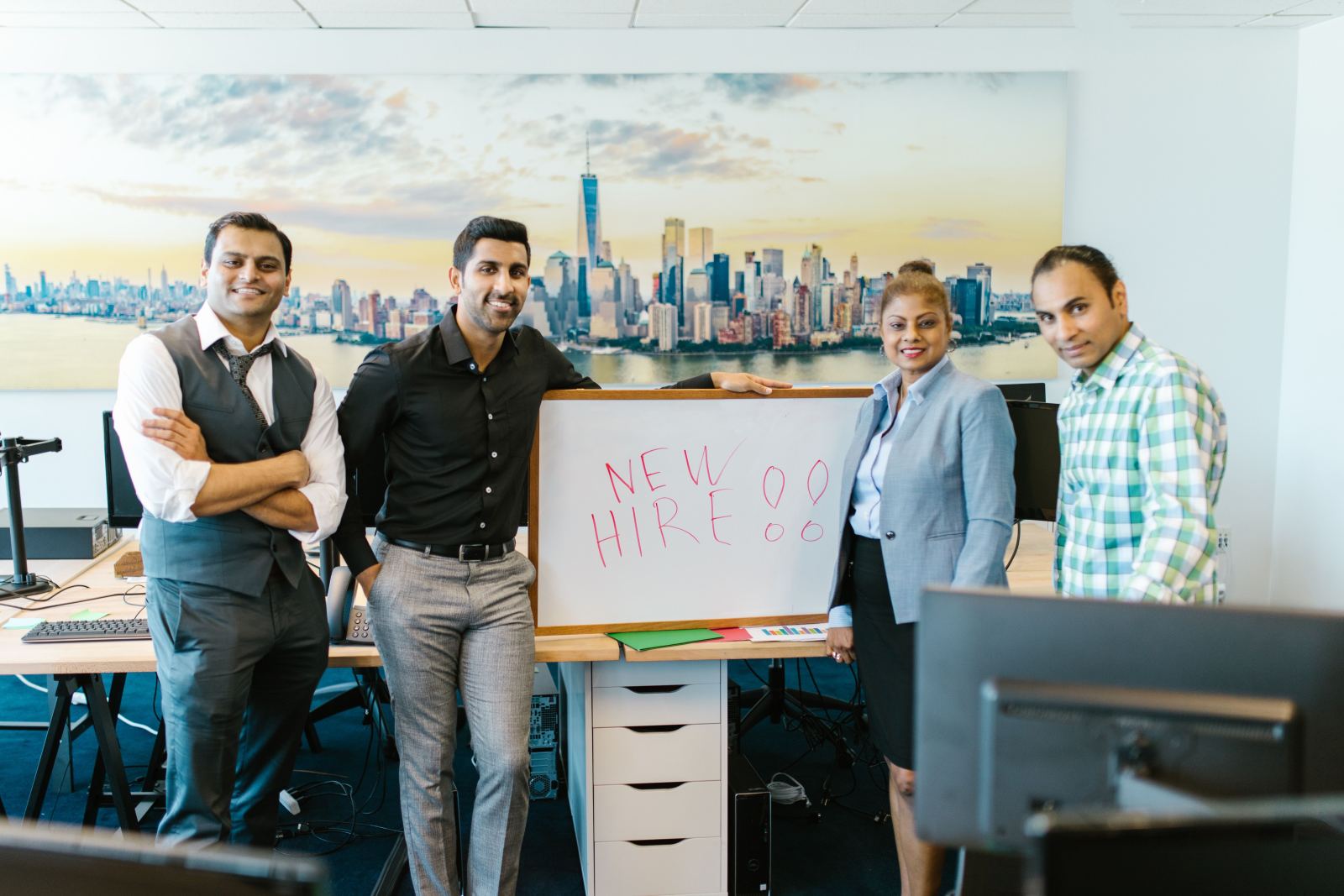 Team standing together with a New Hire sign in an office