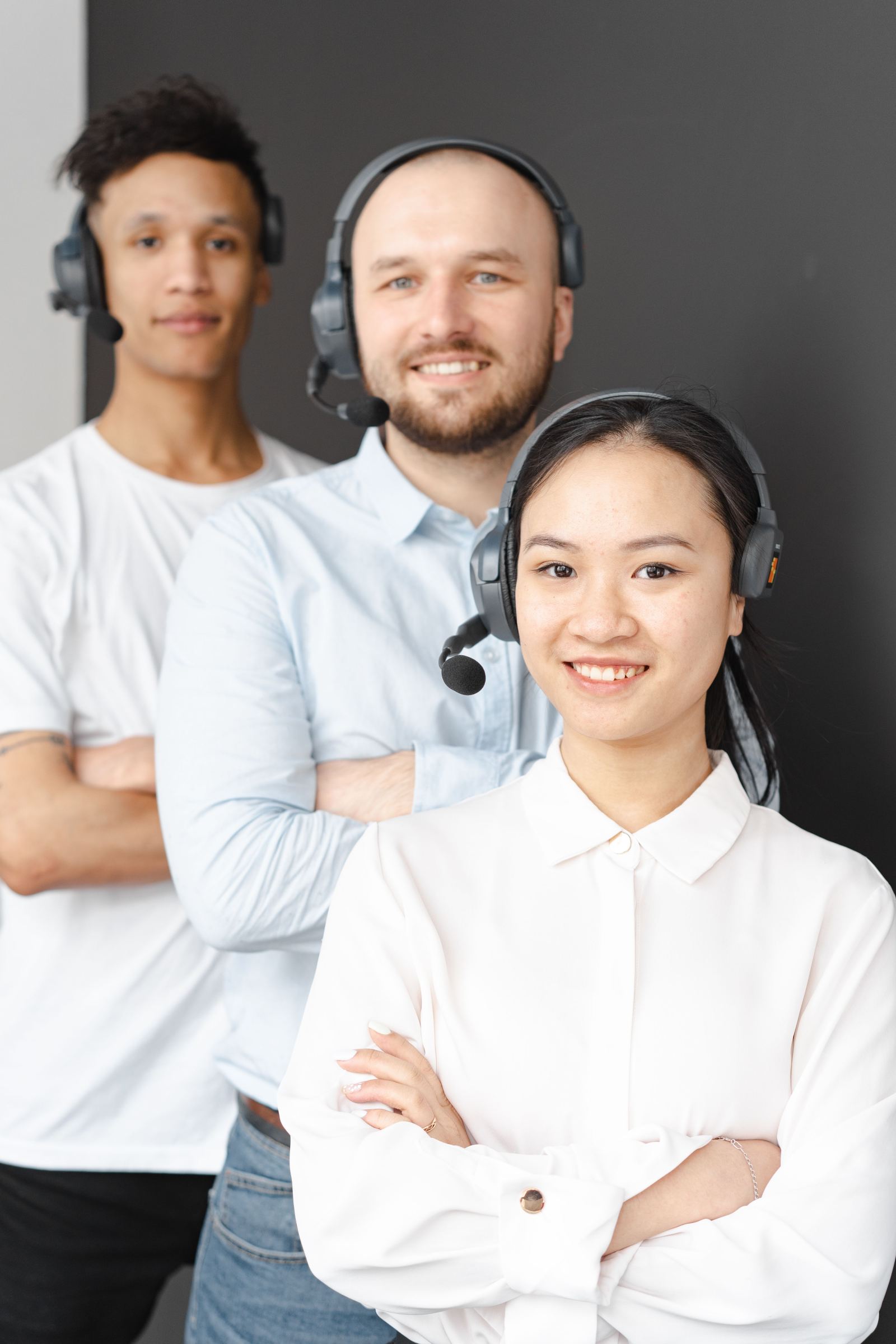 Three call answering agents wearing headsets standing together for a portrait